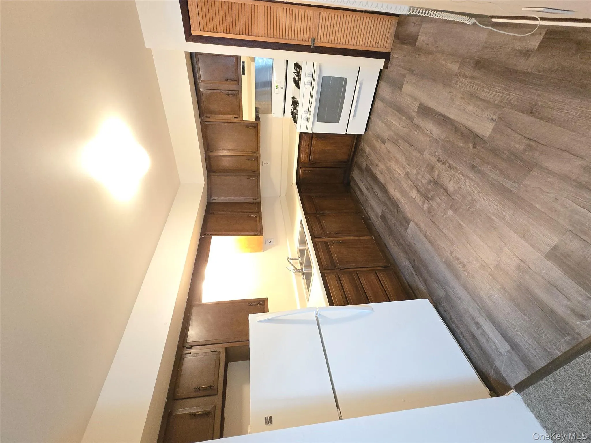 Kitchen featuring refrigerator, light countertops, range, dark wood-style flooring, and dark brown cabinets Kitchen featuring refrigerator, light countertops, range, dark wood-style flooring, and dark brown cabinets