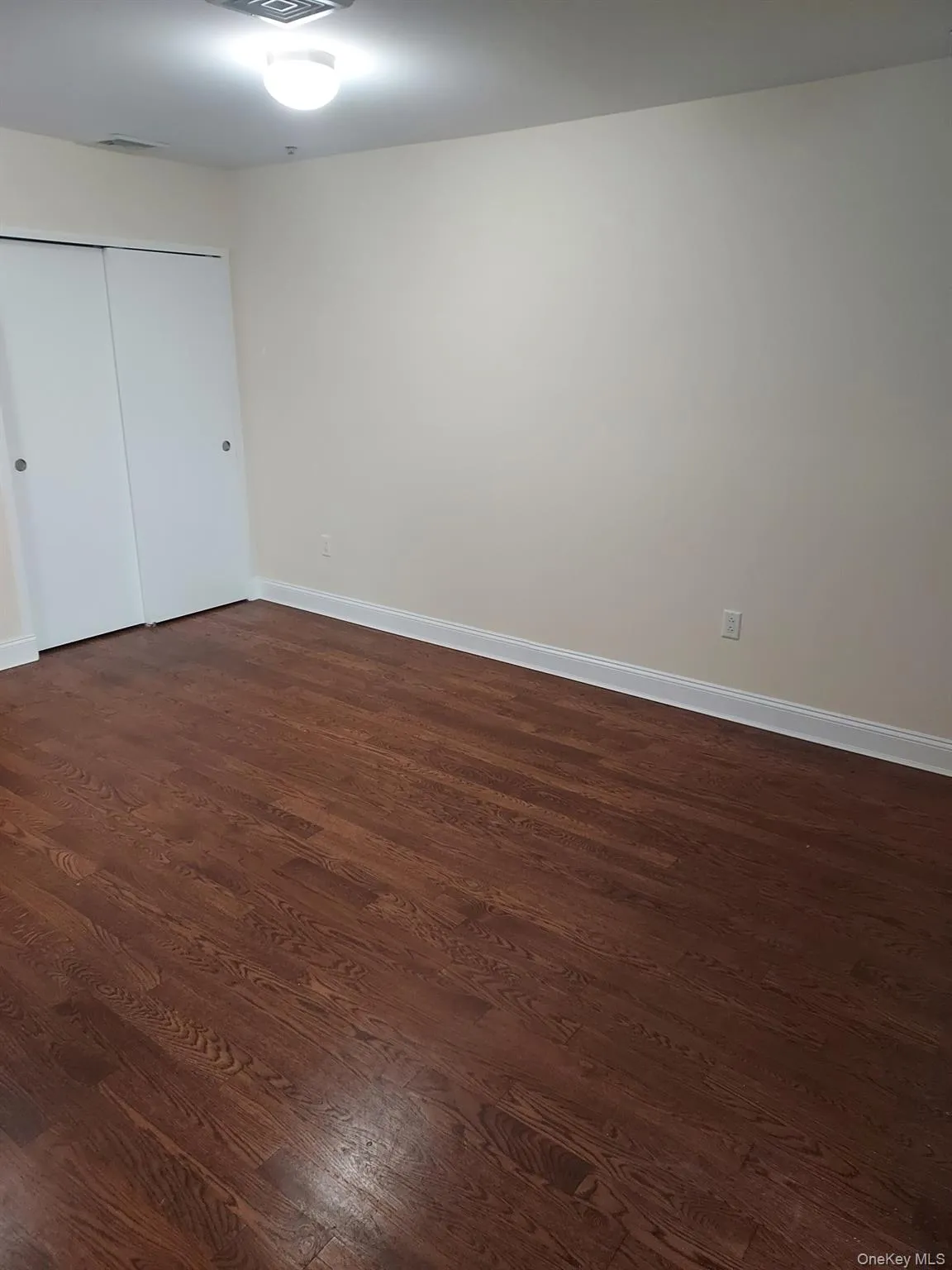 Unfurnished bedroom with dark wood-style floors and a closet Unfurnished bedroom with dark wood-style floors and a closet
