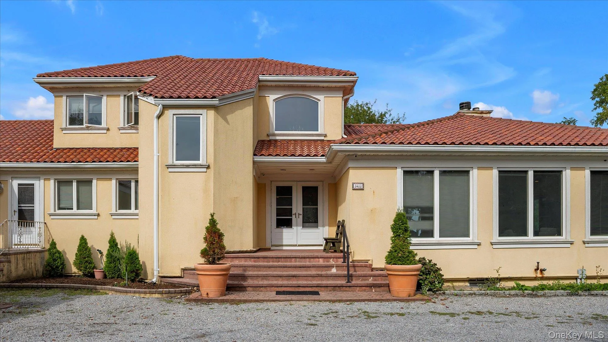 Back of property with stucco siding, a chimney, a tile roof, and french doors Back of property with stucco siding, a chimney, a tile roof, and french doors