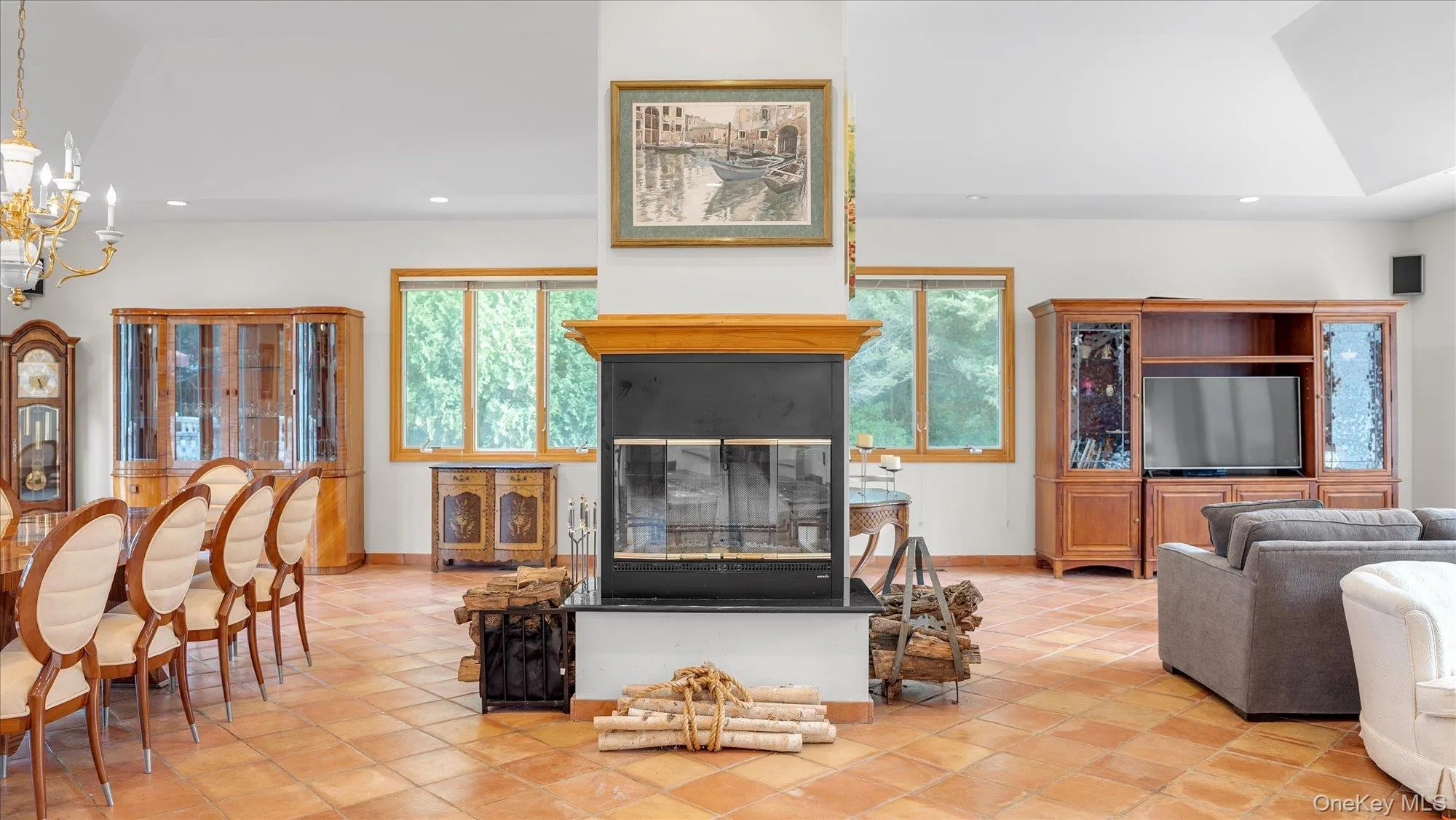 Living room with recessed lighting, light tile patterned floors, a chandelier, and a glass covered fireplace Living room with recessed lighting, light tile patterned floors, a chandelier, and a glass covered fireplace
