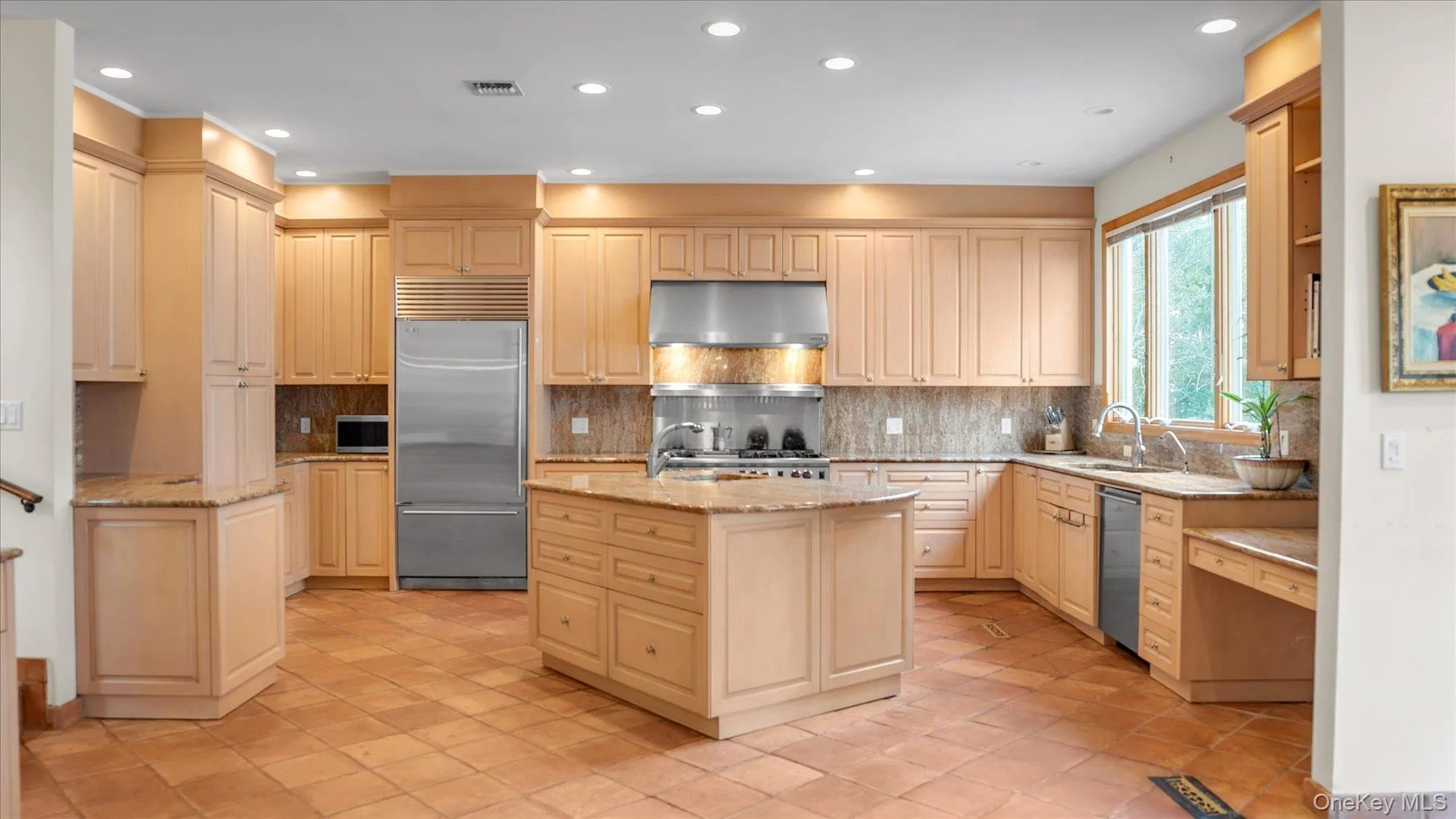 Kitchen with tasteful backsplash, light stone counters, recessed lighting, appliances with stainless steel finishes, and an island with sink Kitchen with tasteful backsplash, light stone counters, recessed lighting, appliances with stainless steel finishes, and an island with sink