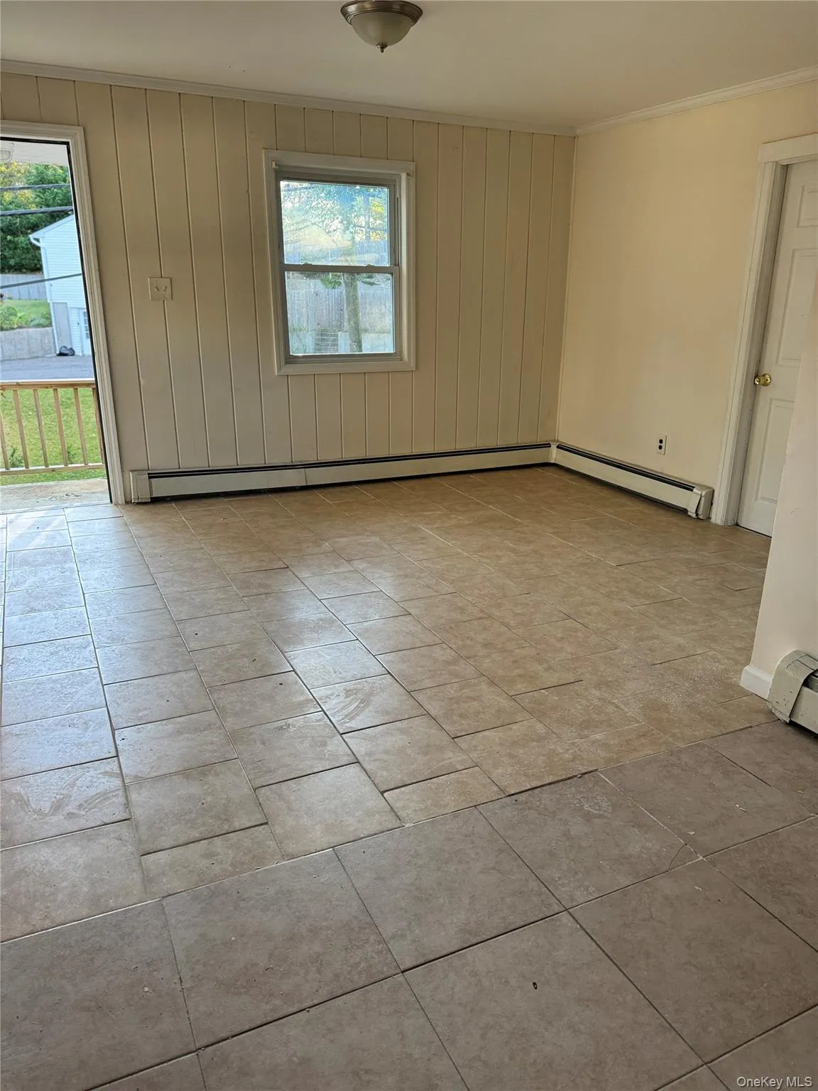 Unfurnished room with wooden walls, crown molding, a baseboard heating unit, and baseboard heating Unfurnished room with wooden walls, crown molding, a baseboard heating unit, and baseboard heating