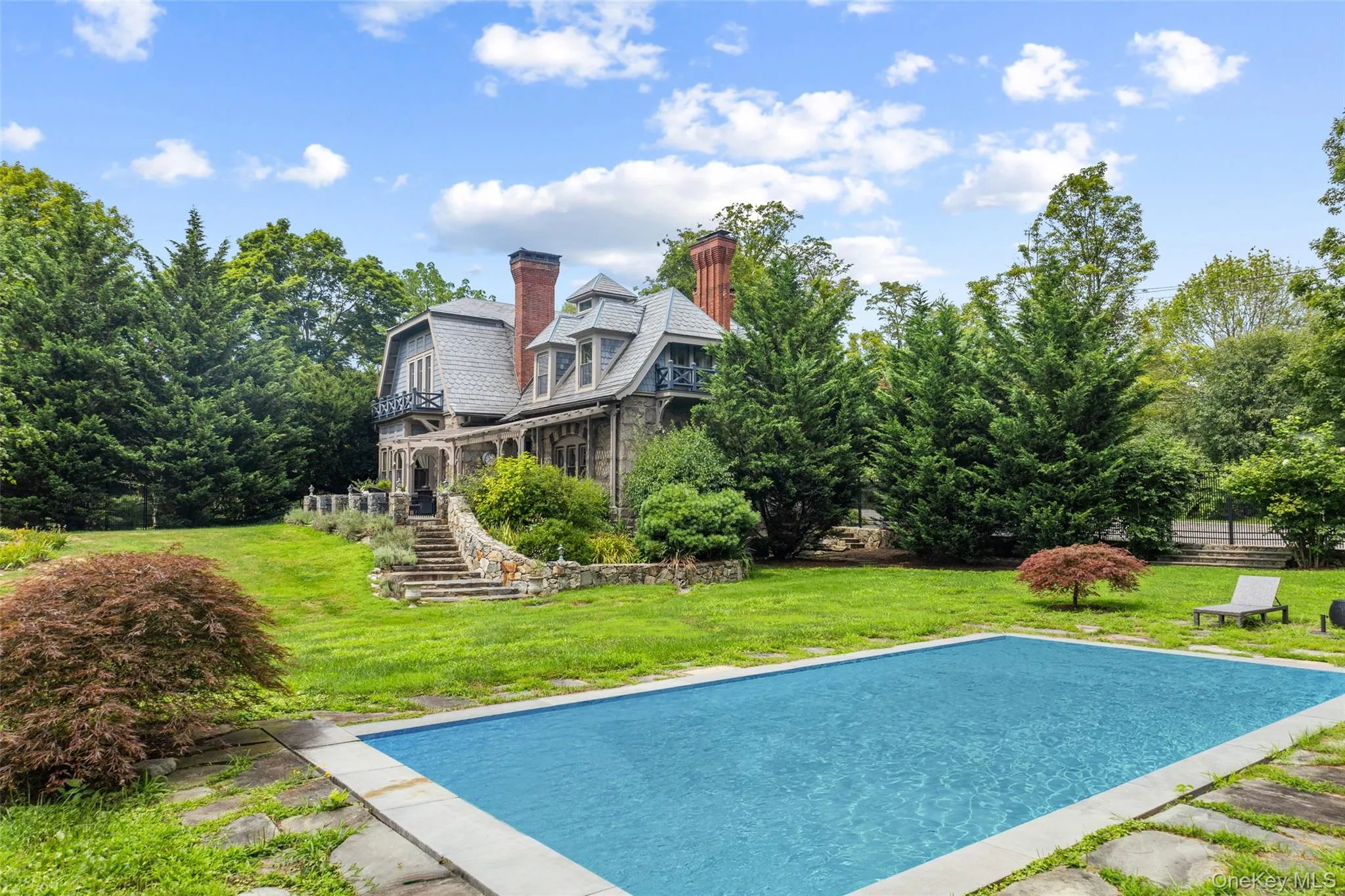 Charming stone patio with steps leading to an in-ground pool Charming stone patio with steps leading to an in-ground pool