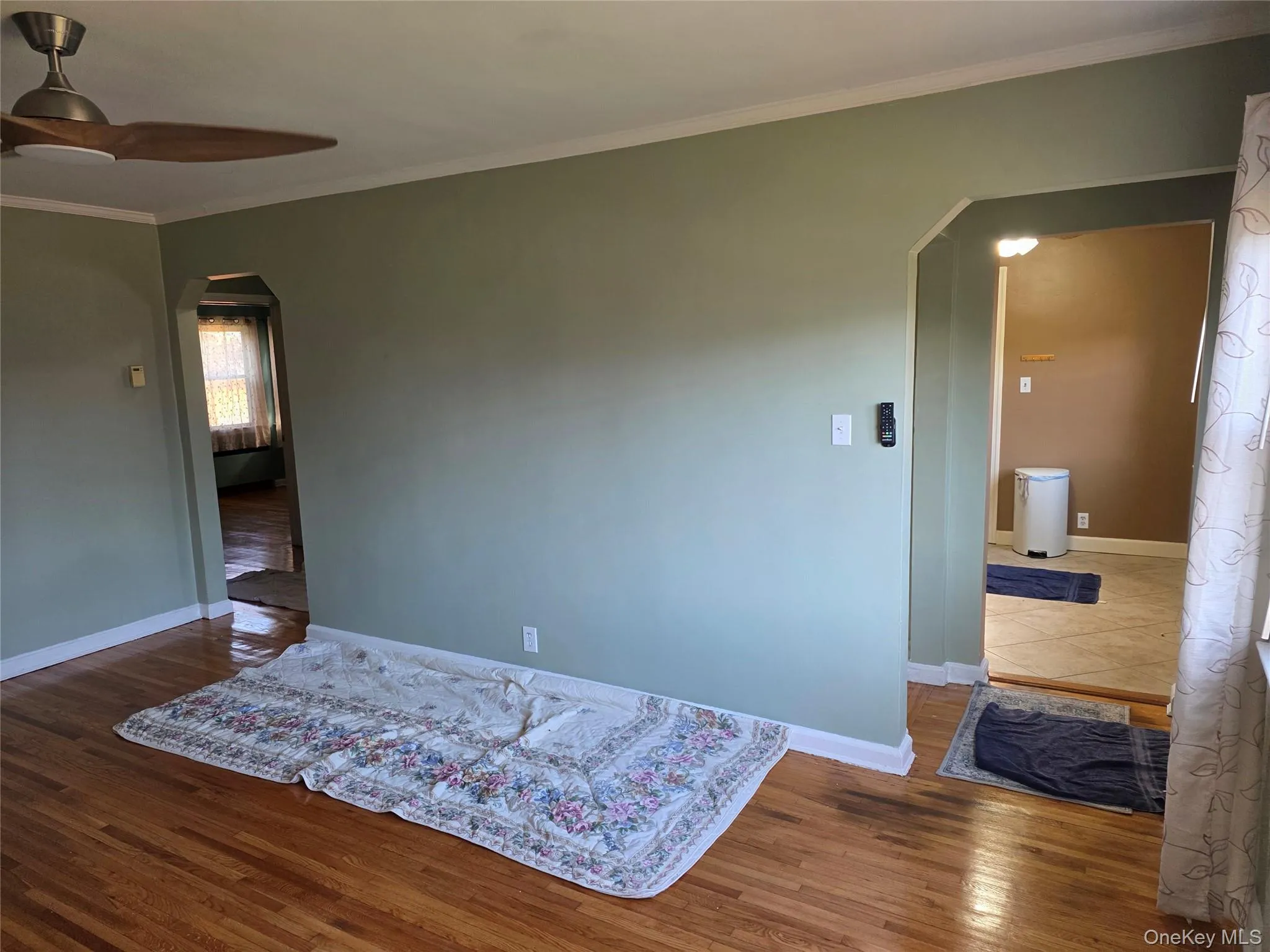 Room featuring arched walkways, ornamental molding, dark wood finished floors, and ceiling fan Room featuring arched walkways, ornamental molding, dark wood finished floors, and ceiling fan