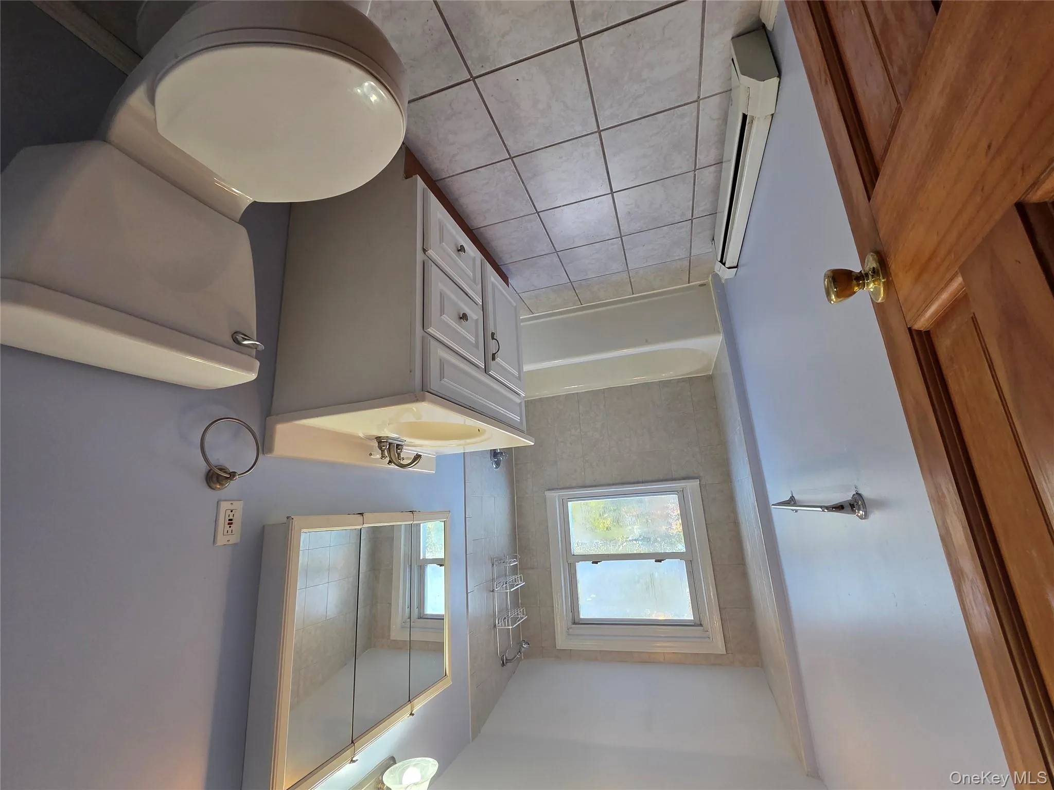 Full bath featuring vanity, shower / tub combination, baseboard heating, and light tile patterned floors Full bath featuring vanity, shower / tub combination, baseboard heating, and light tile patterned floors