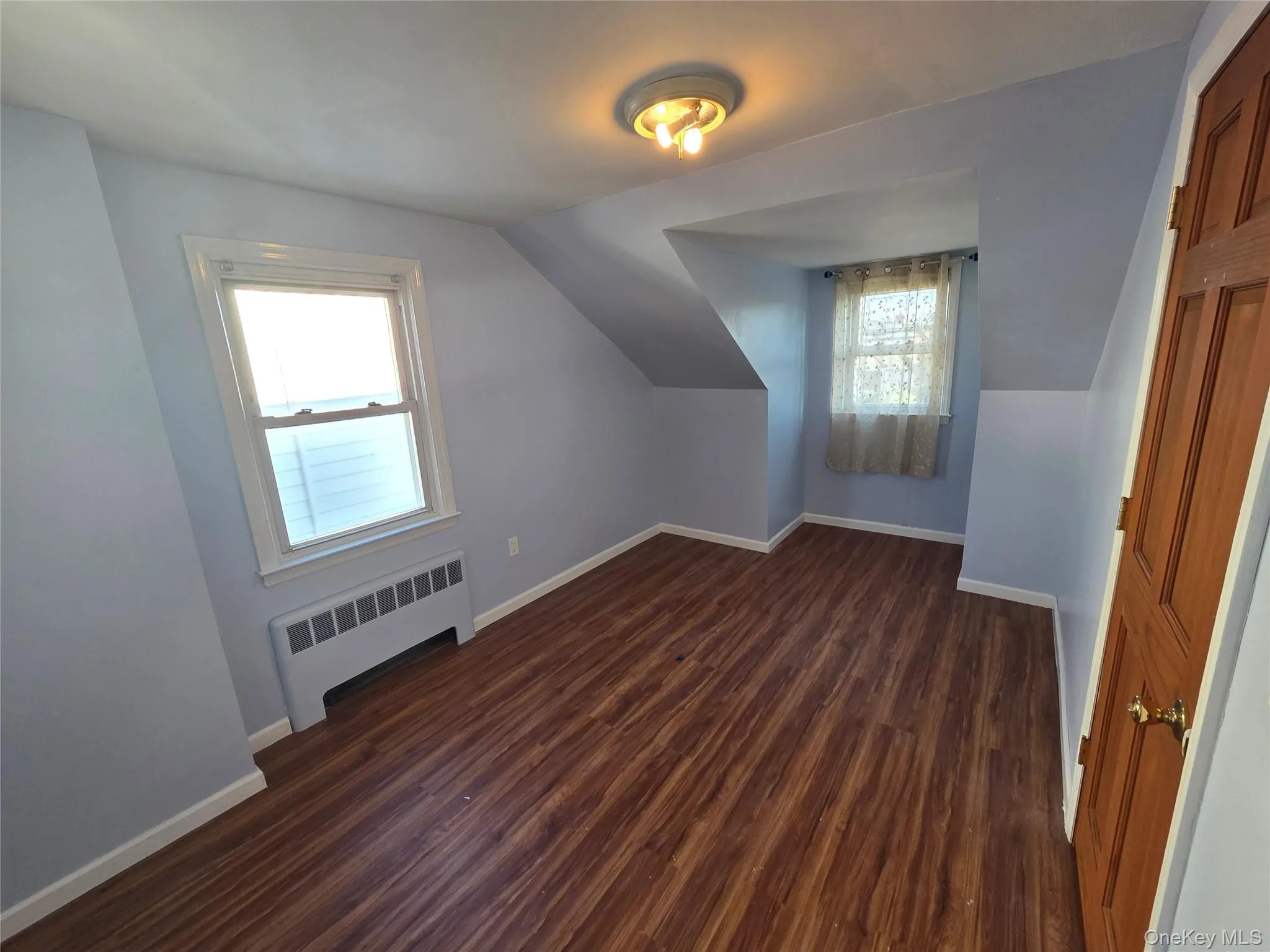 Bedroom - Additional living space featuring dark wood-style flooring, radiator heating unit, and lofted ceiling Bedroom - Additional living space featuring dark wood-style flooring, radiator heating unit, and lofted ceiling