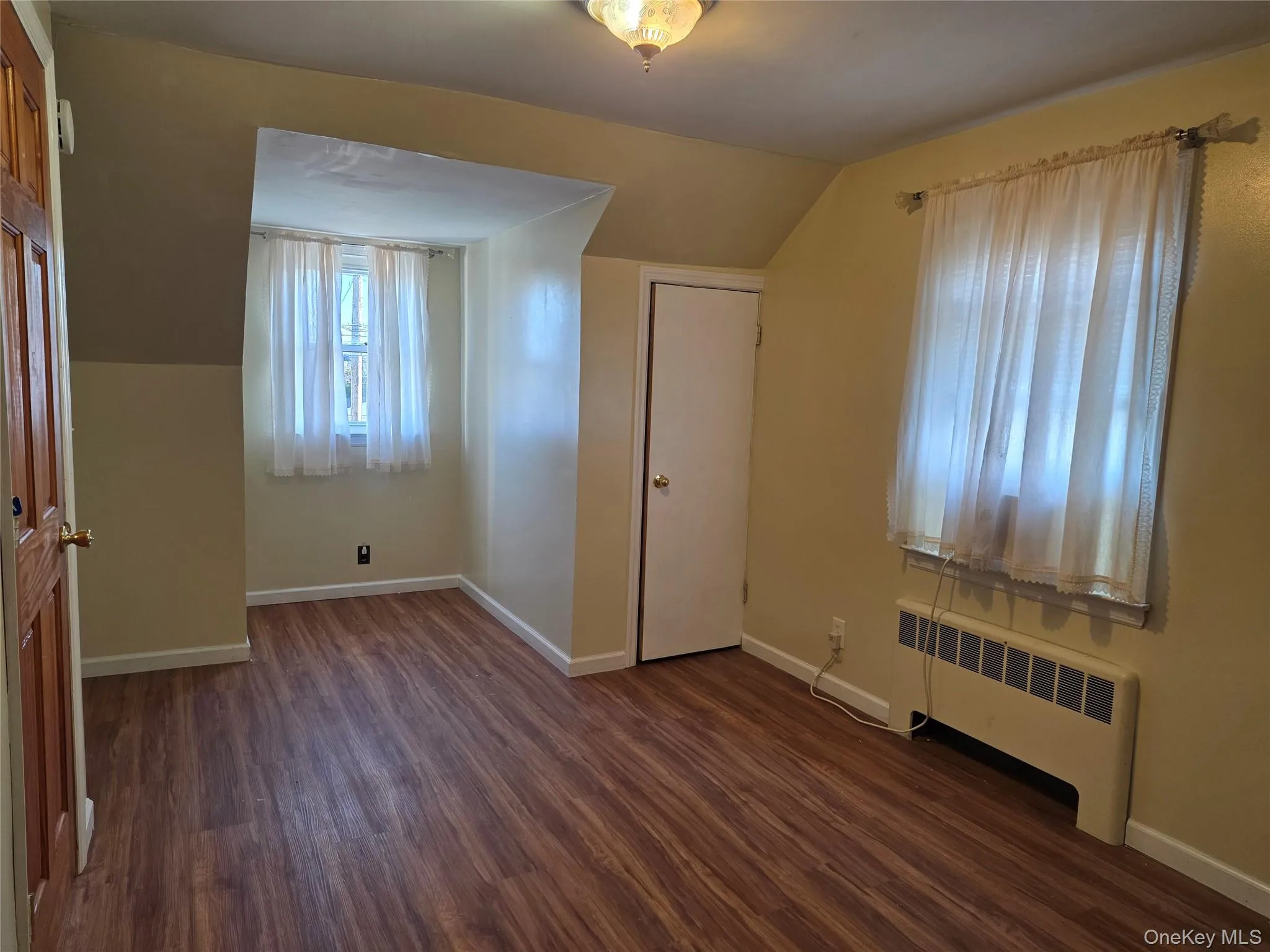 Bedroom radiator, dark wood-style flooring, and lofted ceiling Bedroom radiator, dark wood-style flooring, and lofted ceiling