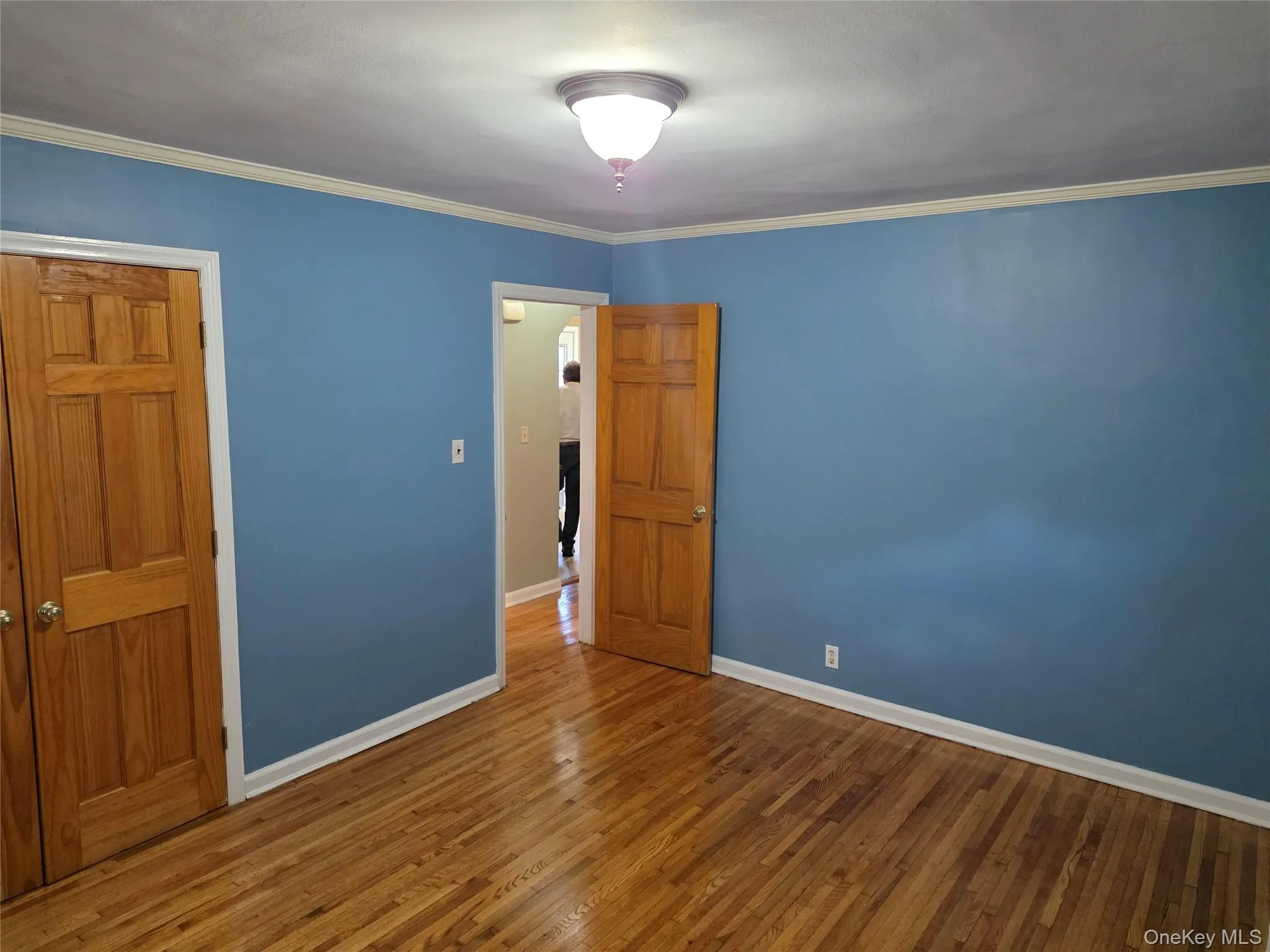 bedroom with wood finished floors, crown molding, and a closet bedroom with wood finished floors, crown molding, and a closet