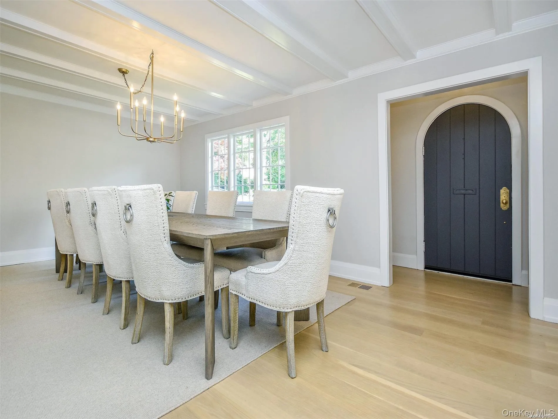 Dining space featuring beam ceiling, arched walkways, light wood-style flooring, and a chandelier Dining space featuring beam ceiling, arched walkways, light wood-style flooring, and a chandelier