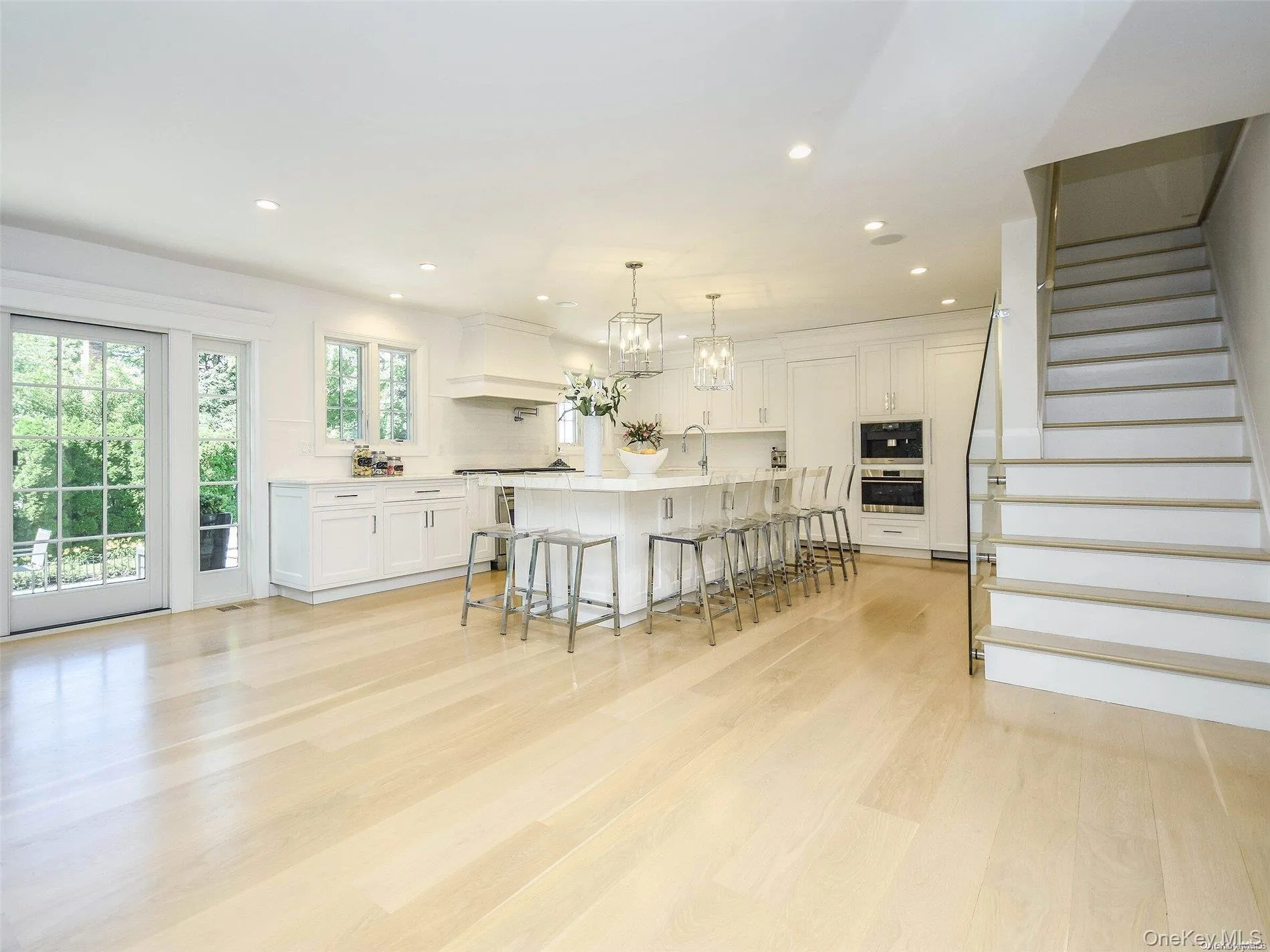 Kitchen with a kitchen breakfast bar, recessed lighting, white cabinets, decorative light fixtures, and a large island with sink Kitchen with a kitchen breakfast bar, recessed lighting, white cabinets, decorative light fixtures, and a large island with sink