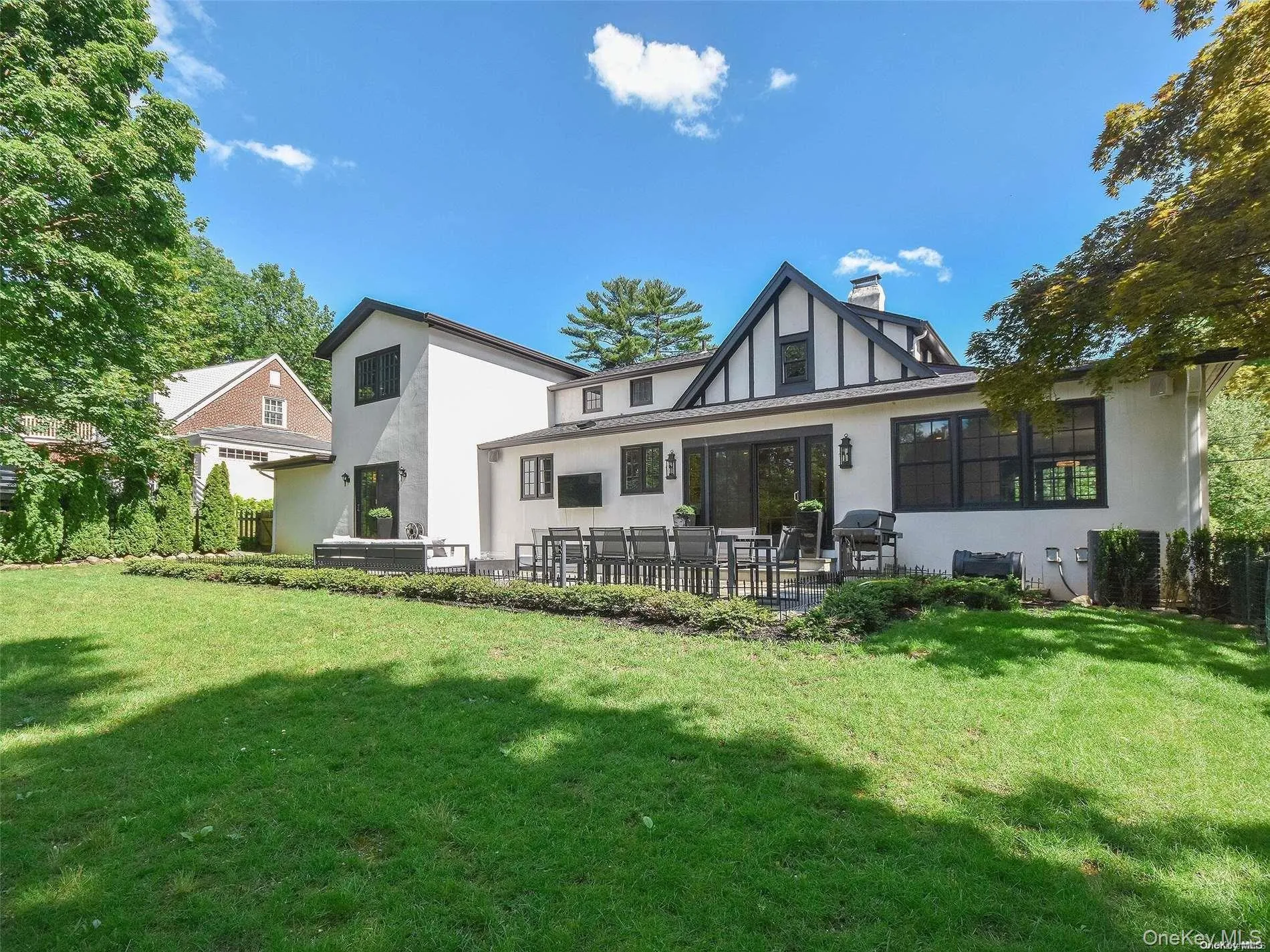 Rear view of house featuring a patio, stucco siding, a lawn, and a chimney Rear view of house featuring a patio, stucco siding, a lawn, and a chimney