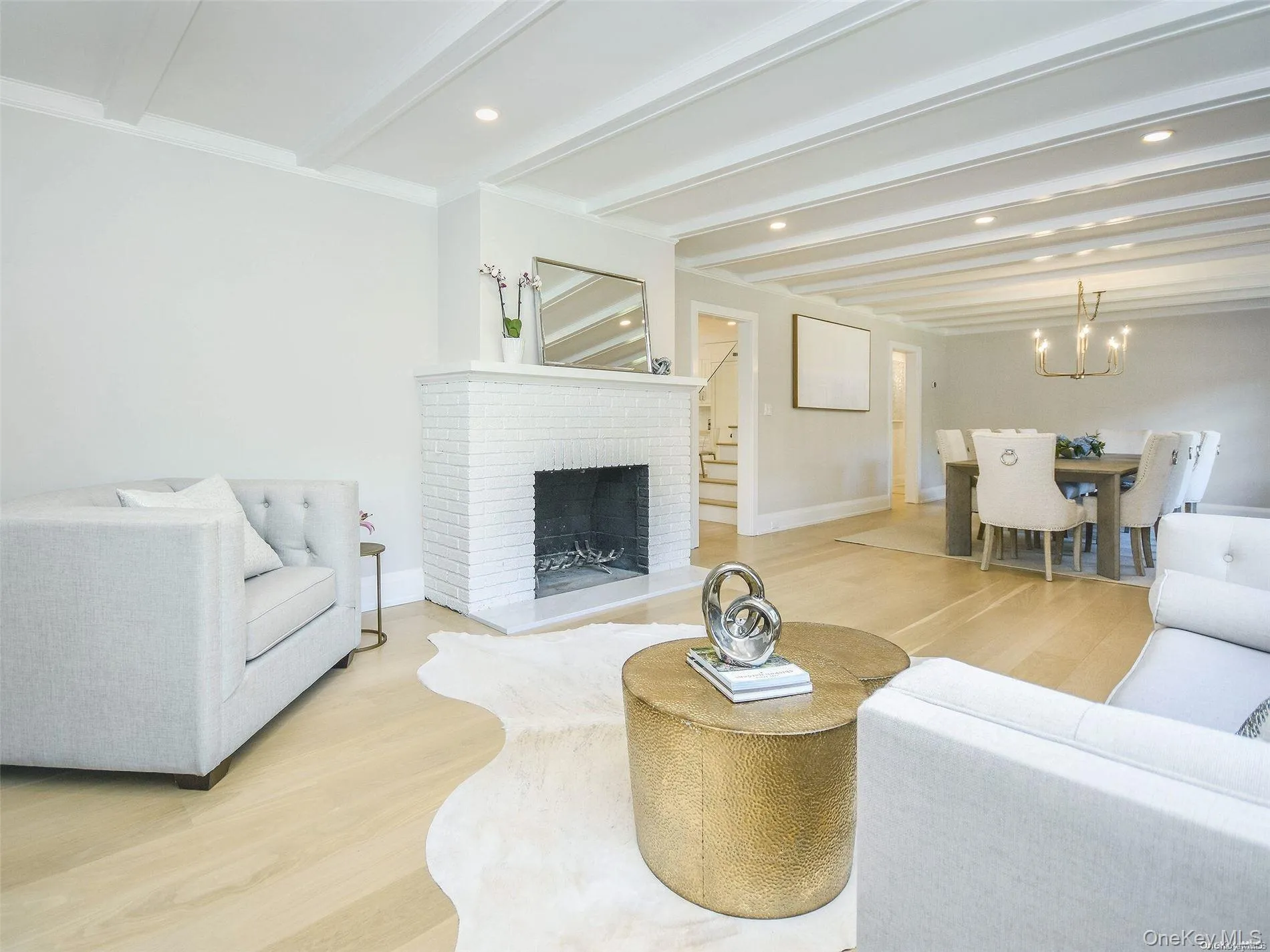 Living room featuring beamed ceiling, light wood-style flooring, a fireplace, a chandelier, and recessed lighting Living room featuring beamed ceiling, light wood-style flooring, a fireplace, a chandelier, and recessed lighting