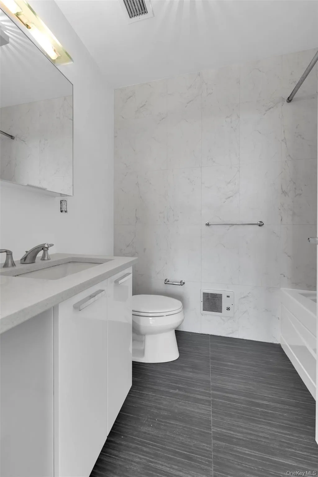 Full bathroom featuring tile walls, vanity, and dark tile patterned flooring Full bathroom featuring tile walls, vanity, and dark tile patterned flooring