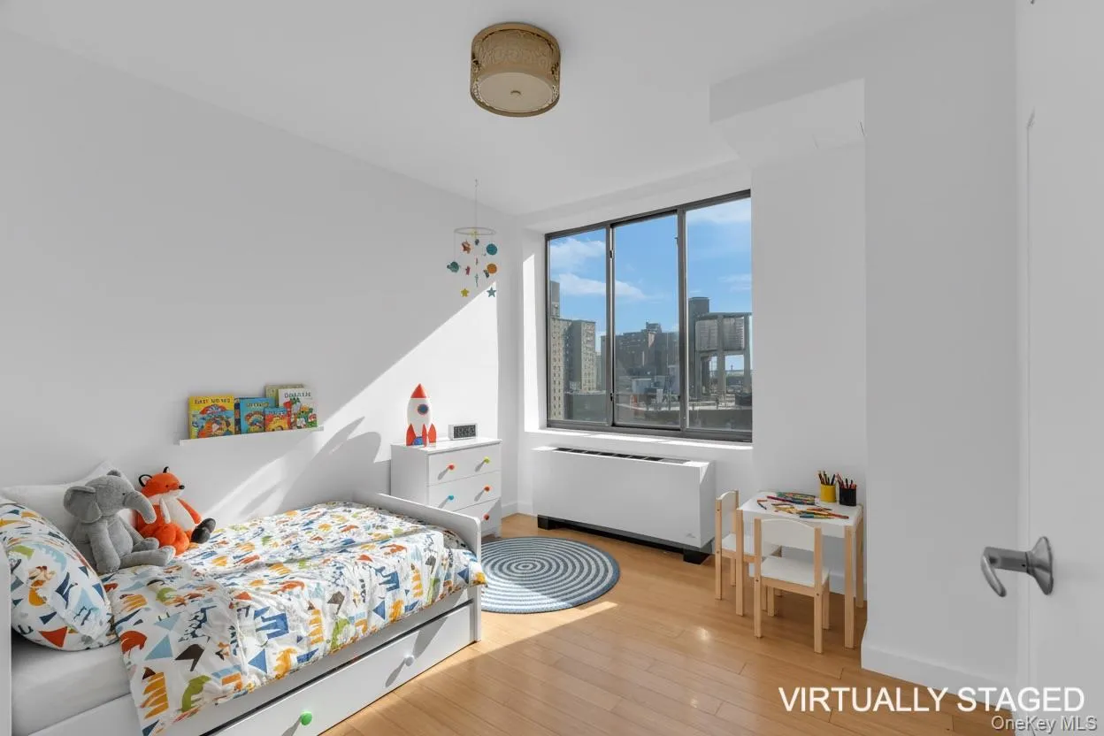 Bedroom with a skyline view, light wood-style flooring, and radiator heating unit Bedroom with a skyline view, light wood-style flooring, and radiator heating unit