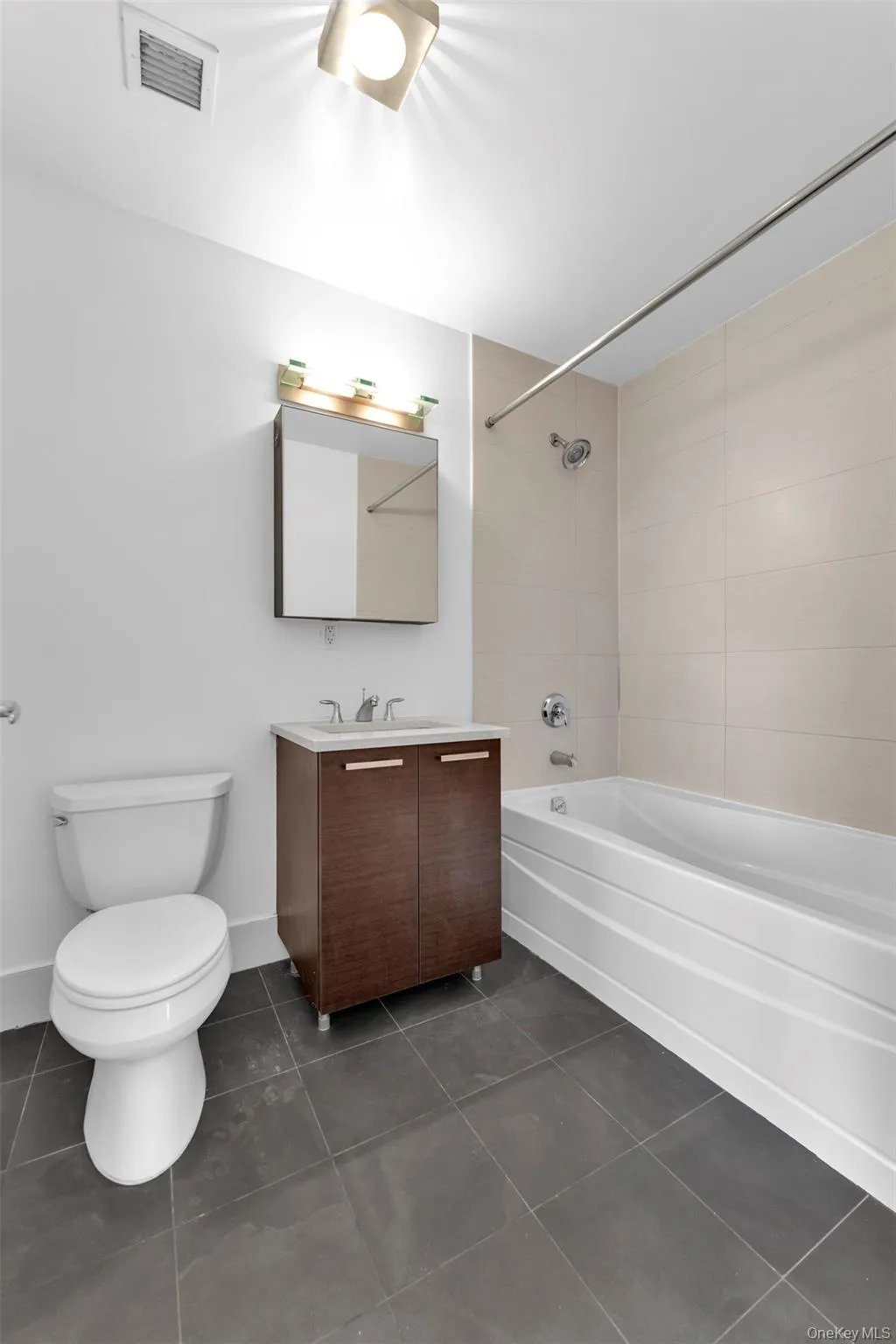 Full bathroom with shower / tub combination, vanity, and dark tile patterned floors Full bathroom with shower / tub combination, vanity, and dark tile patterned floors