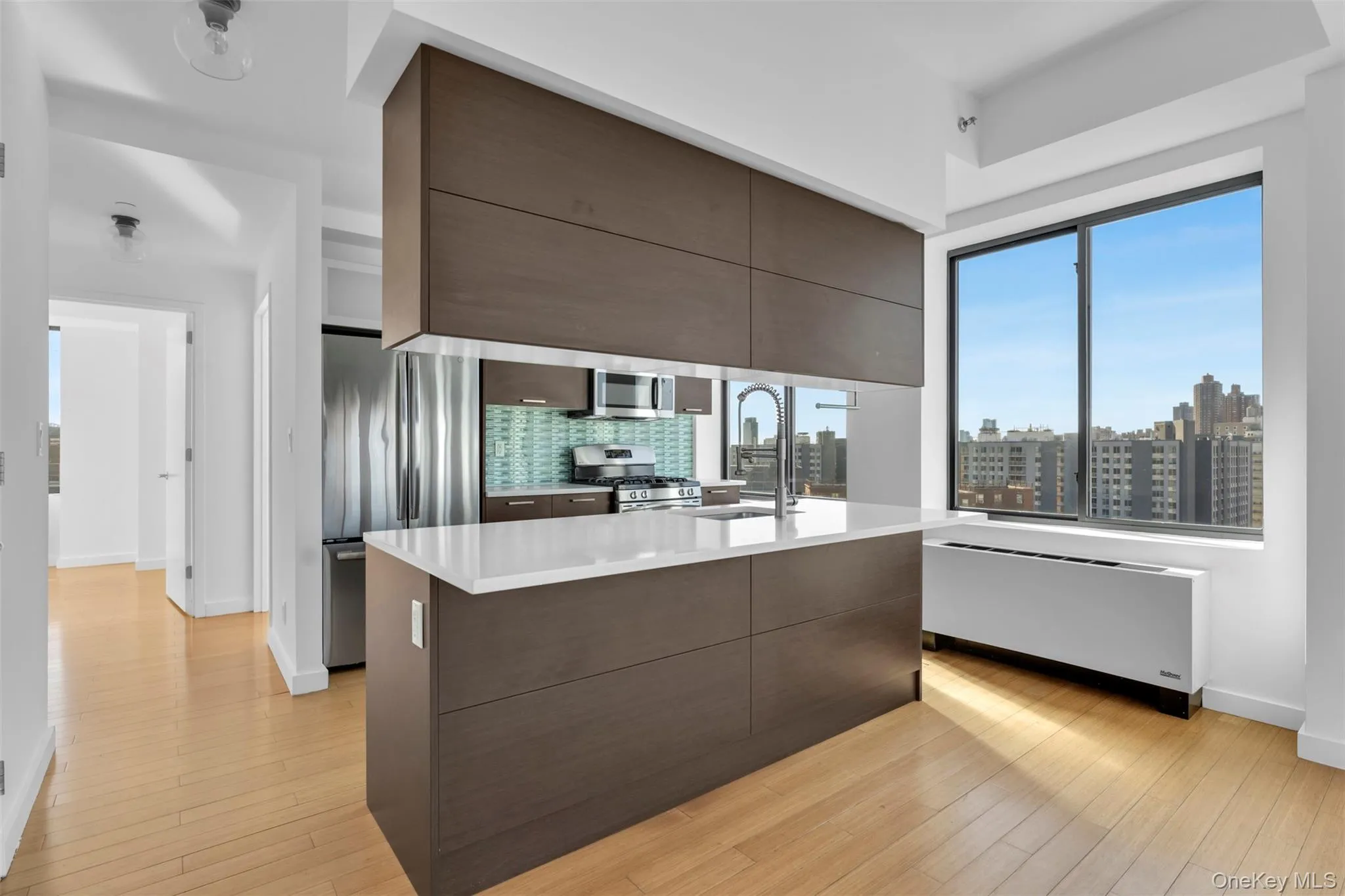 Kitchen with modern cabinets, a kitchen island with sink, a skyline view, appliances with stainless steel finishes, and dark brown cabinets Kitchen with modern cabinets, a kitchen island with sink, a skyline view, appliances with stainless steel finishes, and dark brown cabinets