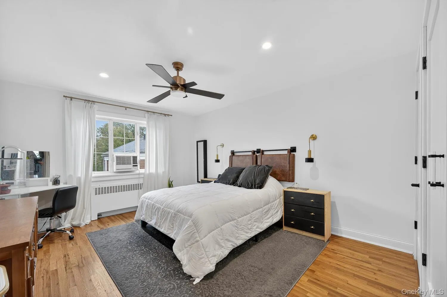 Bedroom with radiator, light wood finished floors, ceiling fan, recessed lighting, and a desk Bedroom with radiator, light wood finished floors, ceiling fan, recessed lighting, and a desk