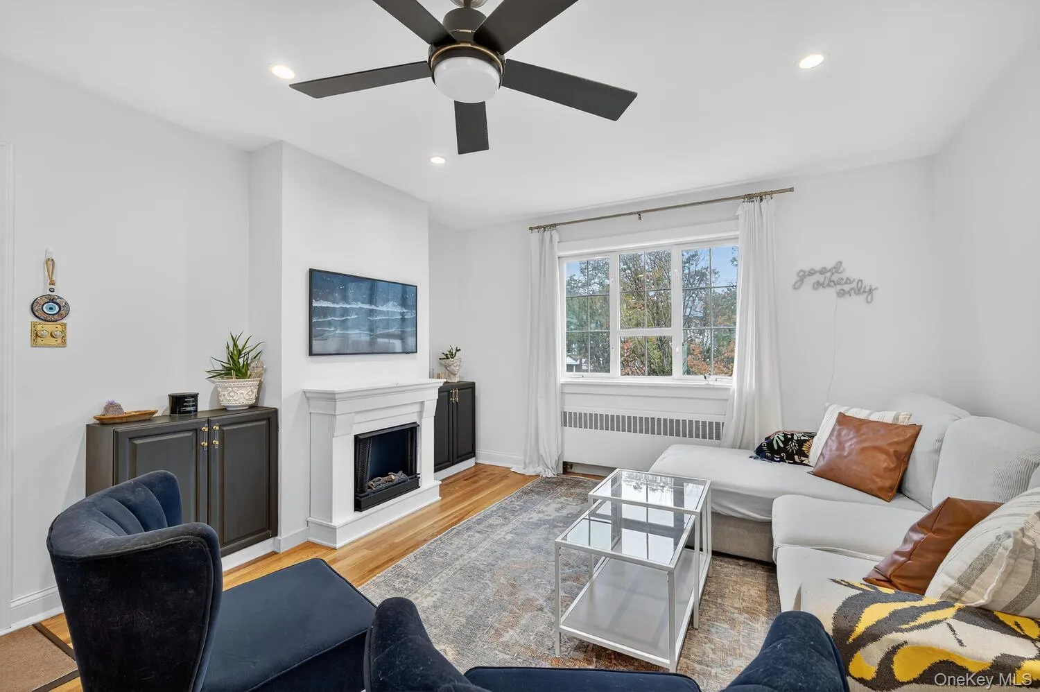 Living area with recessed lighting, radiator, and wood finished floors Living area with recessed lighting, radiator, and wood finished floors
