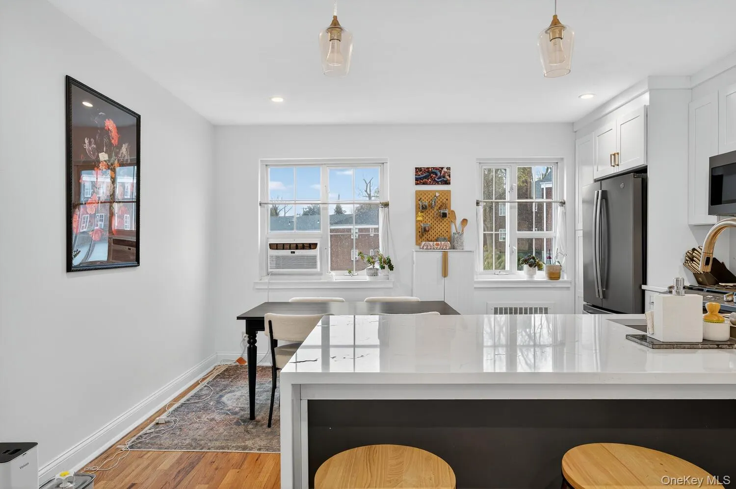 Kitchen featuring light stone countertops, appliances with stainless steel finishes, light wood-type flooring, a breakfast bar area, and white cabinets Kitchen featuring light stone countertops, appliances with stainless steel finishes, light wood-type flooring, a breakfast bar area, and white cabinets