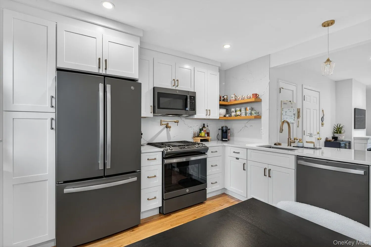 Kitchen with stainless steel appliances, white cabinets, light wood-style flooring, open shelves, and recessed lighting Kitchen with stainless steel appliances, white cabinets, light wood-style flooring, open shelves, and recessed lighting