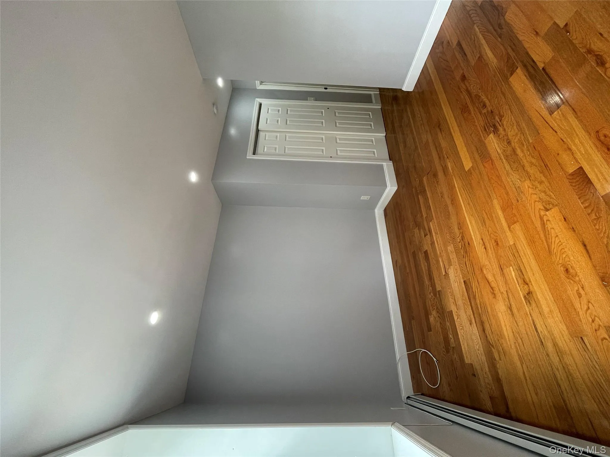 Empty room featuring baseboard heating, recessed lighting, and wood finished floors Empty room featuring baseboard heating, recessed lighting, and wood finished floors