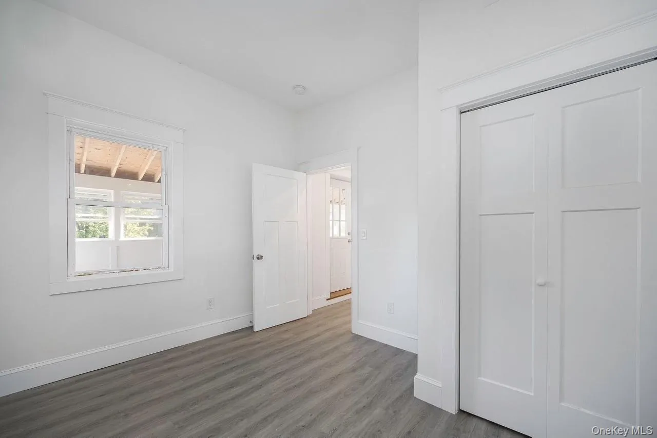 Unfurnished bedroom with multiple windows, wood finished floors, and a closet Unfurnished bedroom with multiple windows, wood finished floors, and a closet
