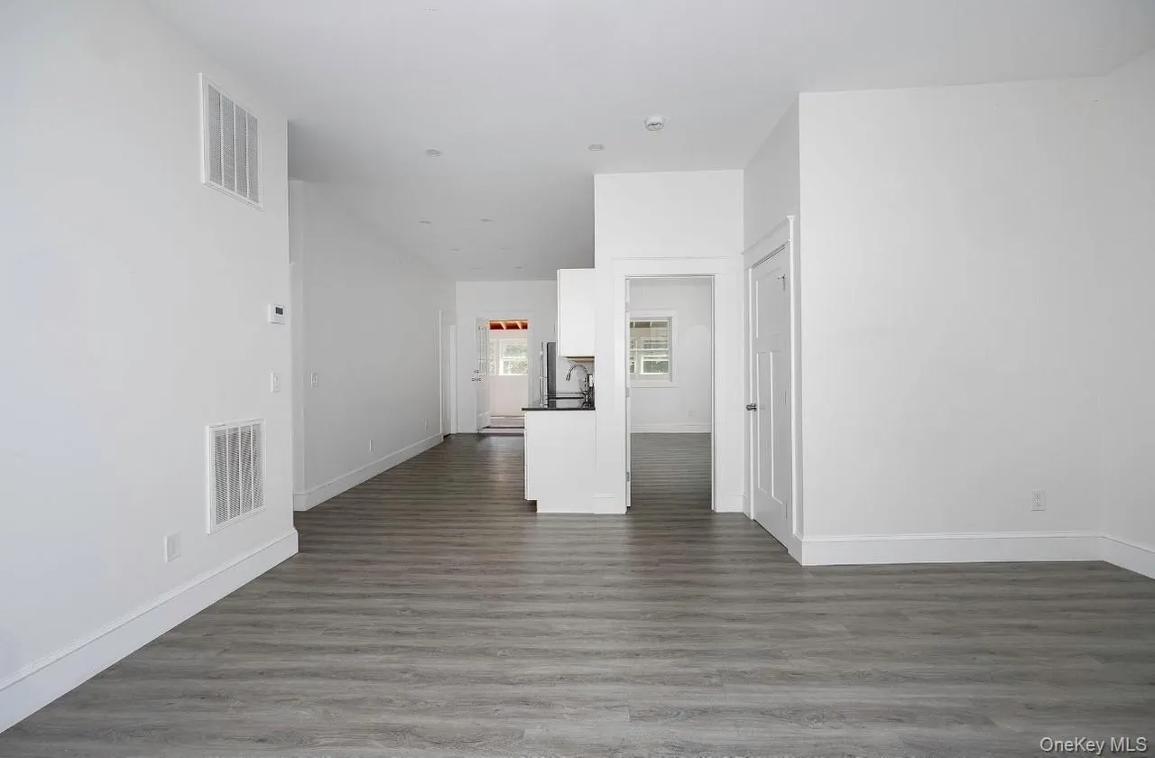 Spare room featuring dark wood-type flooring and baseboards Spare room featuring dark wood-type flooring and baseboards