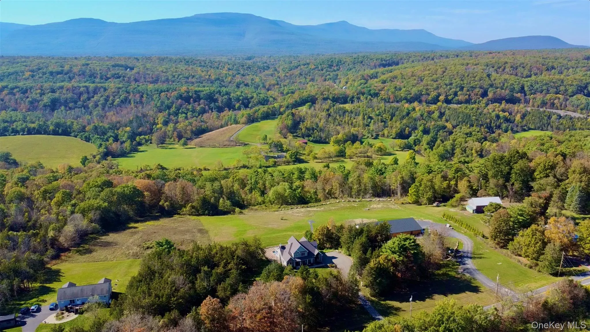 Aerial view of property's location featuring a heavily wooded area and a mountain backdrop Aerial view of property's location featuring a heavily wooded area and a mountain backdrop