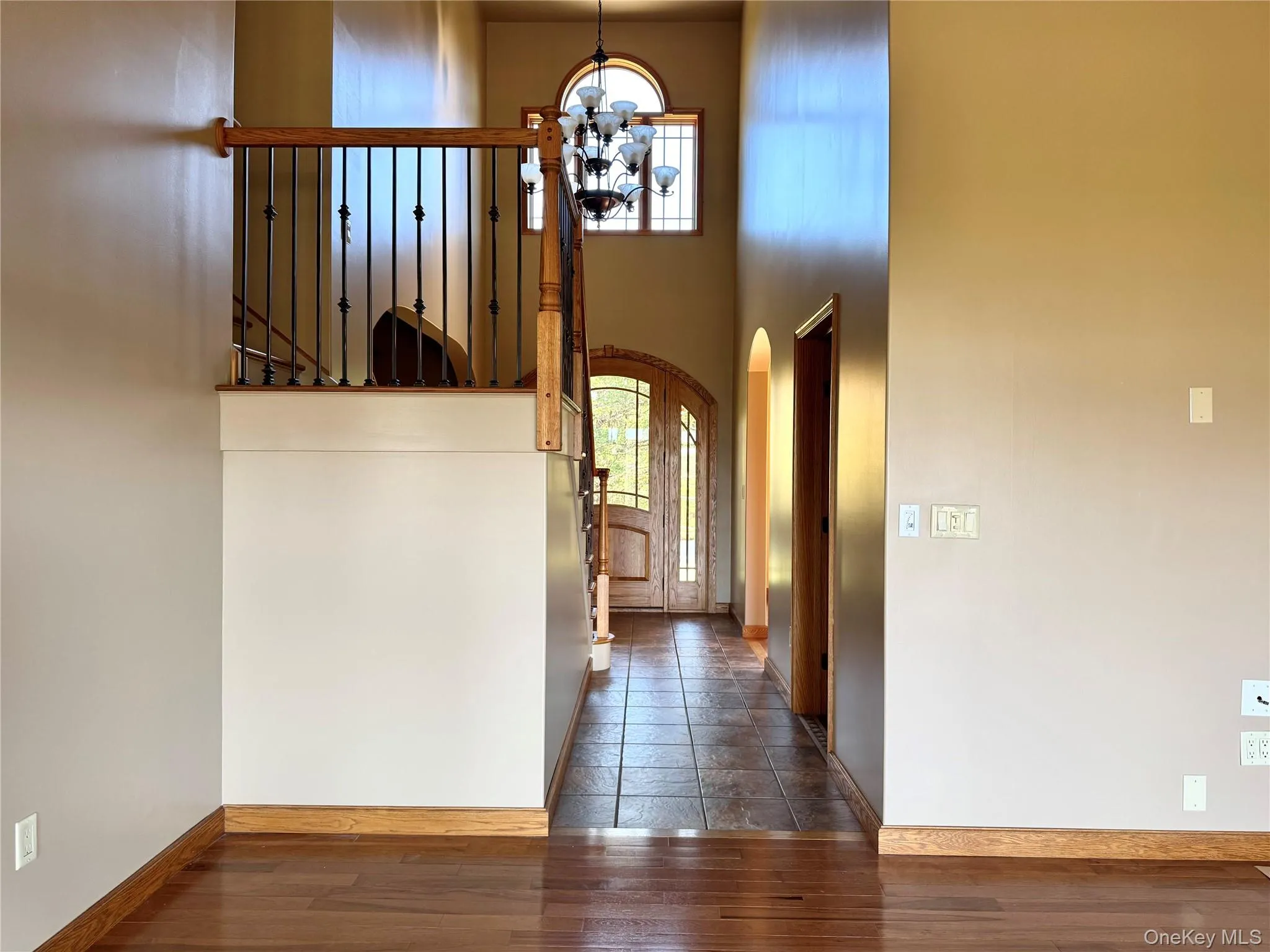 Foyer with arched walkways, a chandelier, a high ceiling, and dark wood finished floors Foyer with arched walkways, a chandelier, a high ceiling, and dark wood finished floors