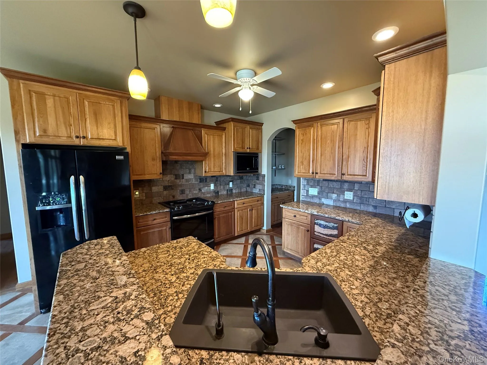 Kitchen with black appliances, decorative backsplash, ceiling fan, recessed lighting, and brown cabinets Kitchen with black appliances, decorative backsplash, ceiling fan, recessed lighting, and brown cabinets
