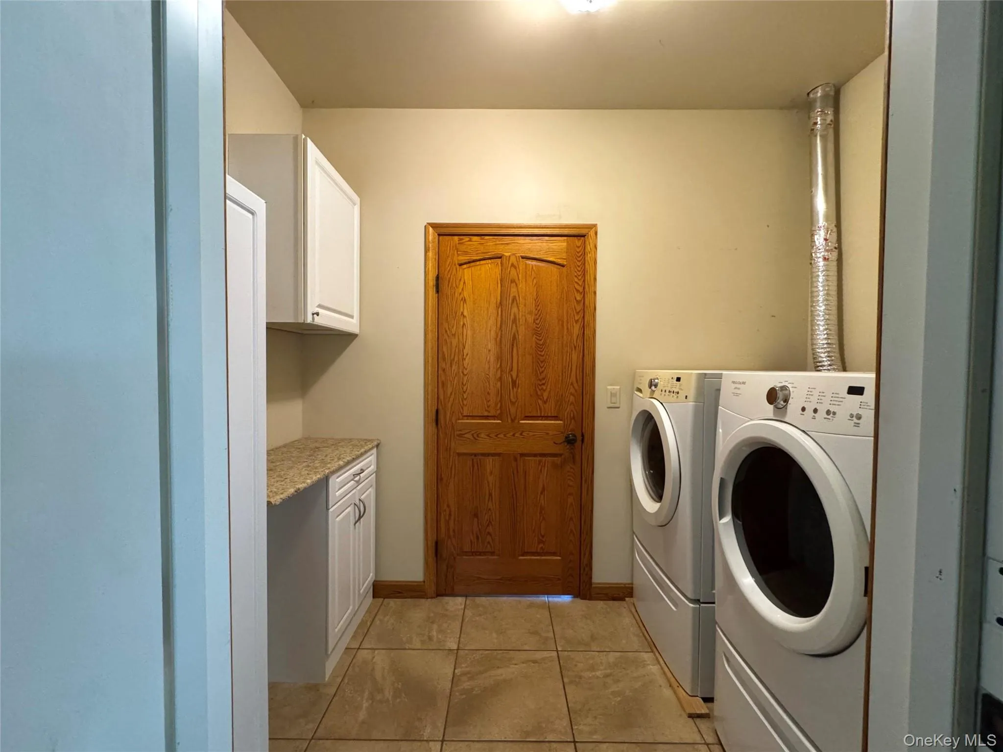 Washroom featuring light tile patterned floors, independent washer and dryer, and cabinet space Washroom featuring light tile patterned floors, independent washer and dryer, and cabinet space