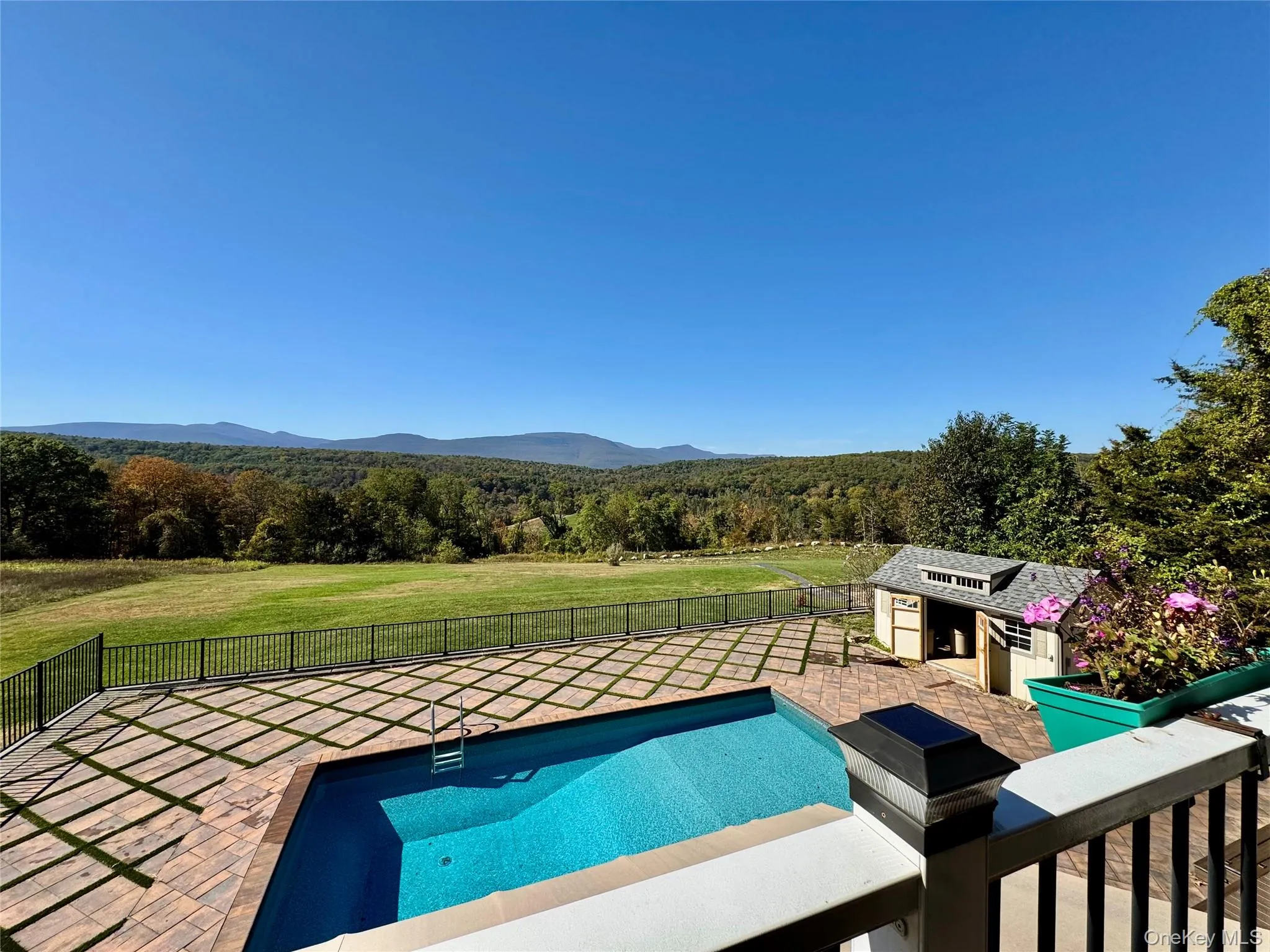 View of swimming pool featuring a wooded view, a patio, a fenced backyard, a mountain view, and an outdoor structure View of swimming pool featuring a wooded view, a patio, a fenced backyard, a mountain view, and an outdoor structure