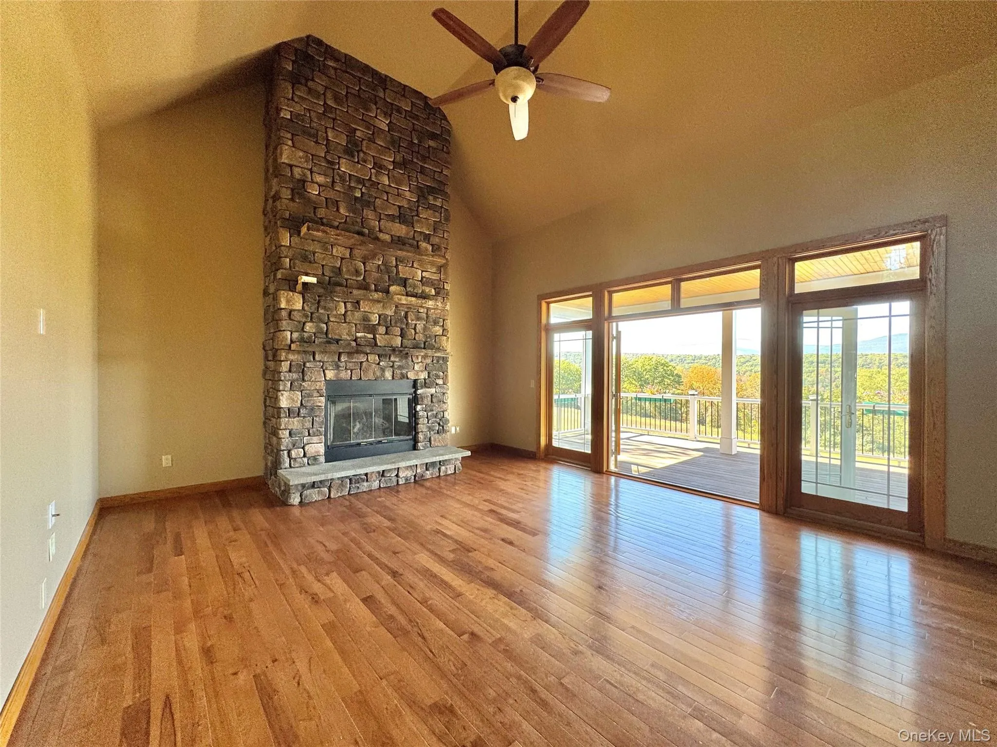 Unfurnished living room with high vaulted ceiling, wood finished floors, a fireplace, and ceiling fan Unfurnished living room with high vaulted ceiling, wood finished floors, a fireplace, and ceiling fan