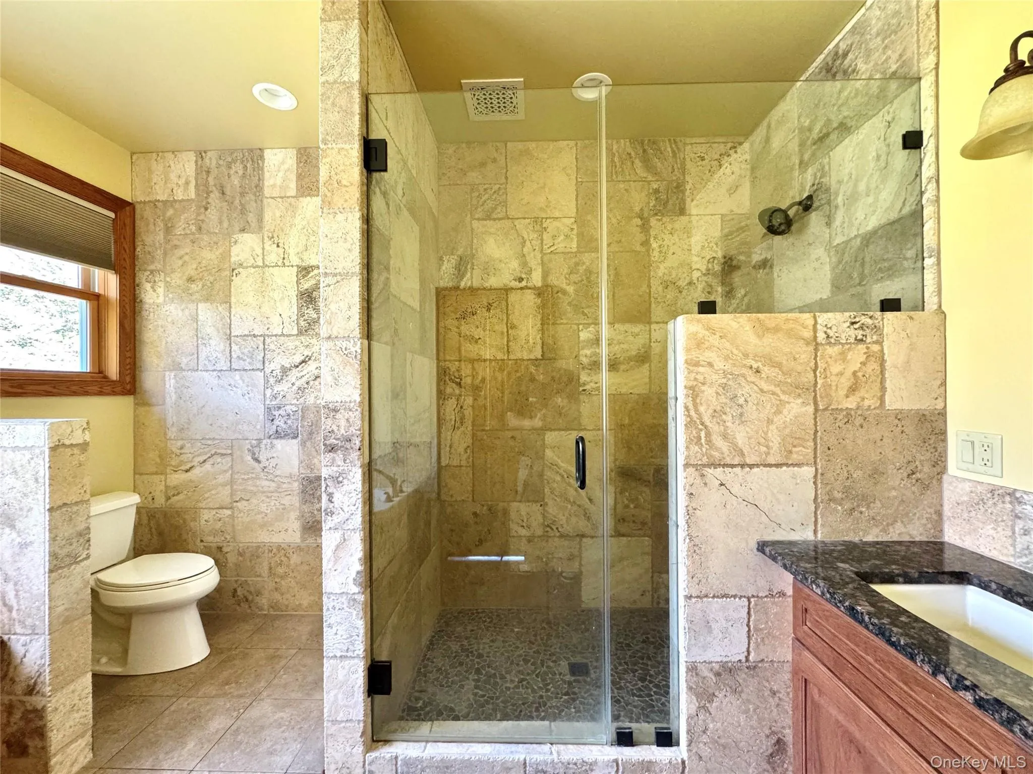 Bathroom with vanity, a shower stall, light tile patterned floors, and tile walls Bathroom with vanity, a shower stall, light tile patterned floors, and tile walls