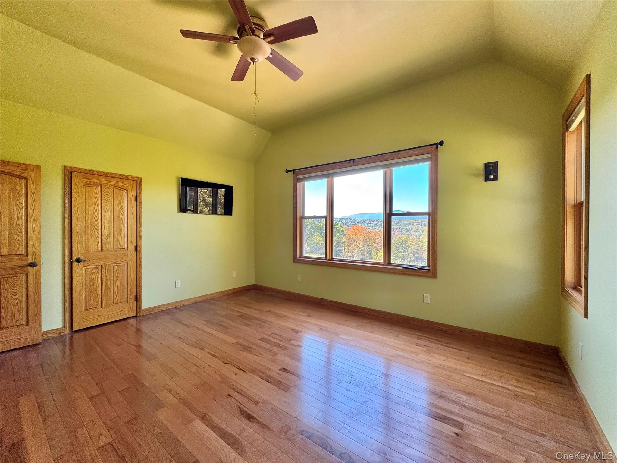 Unfurnished room featuring vaulted ceiling, wood-type flooring, and a ceiling fan Unfurnished room featuring vaulted ceiling, wood-type flooring, and a ceiling fan