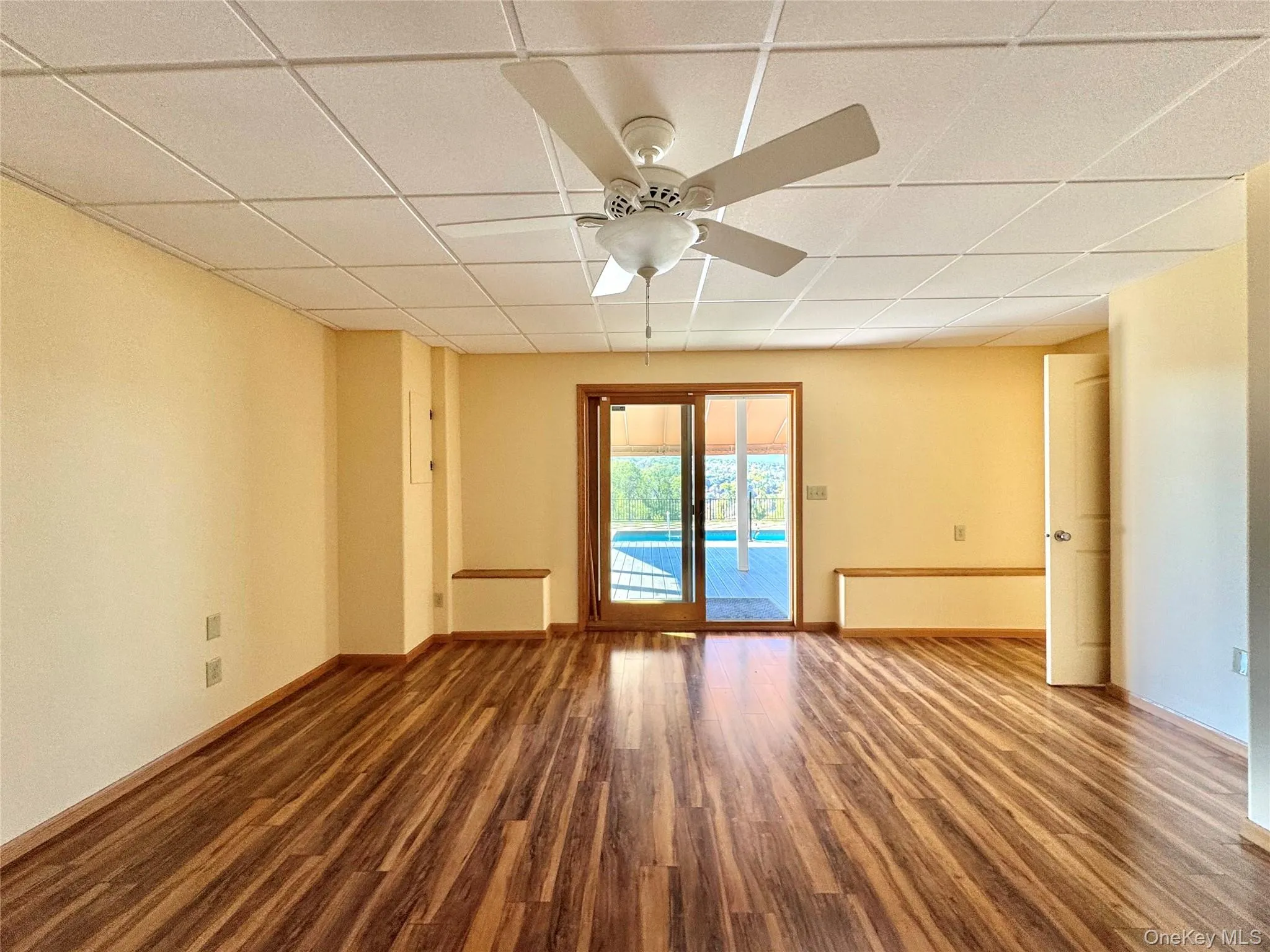 Unfurnished room featuring a paneled ceiling, wood finished floors, and a ceiling fan Unfurnished room featuring a paneled ceiling, wood finished floors, and a ceiling fan
