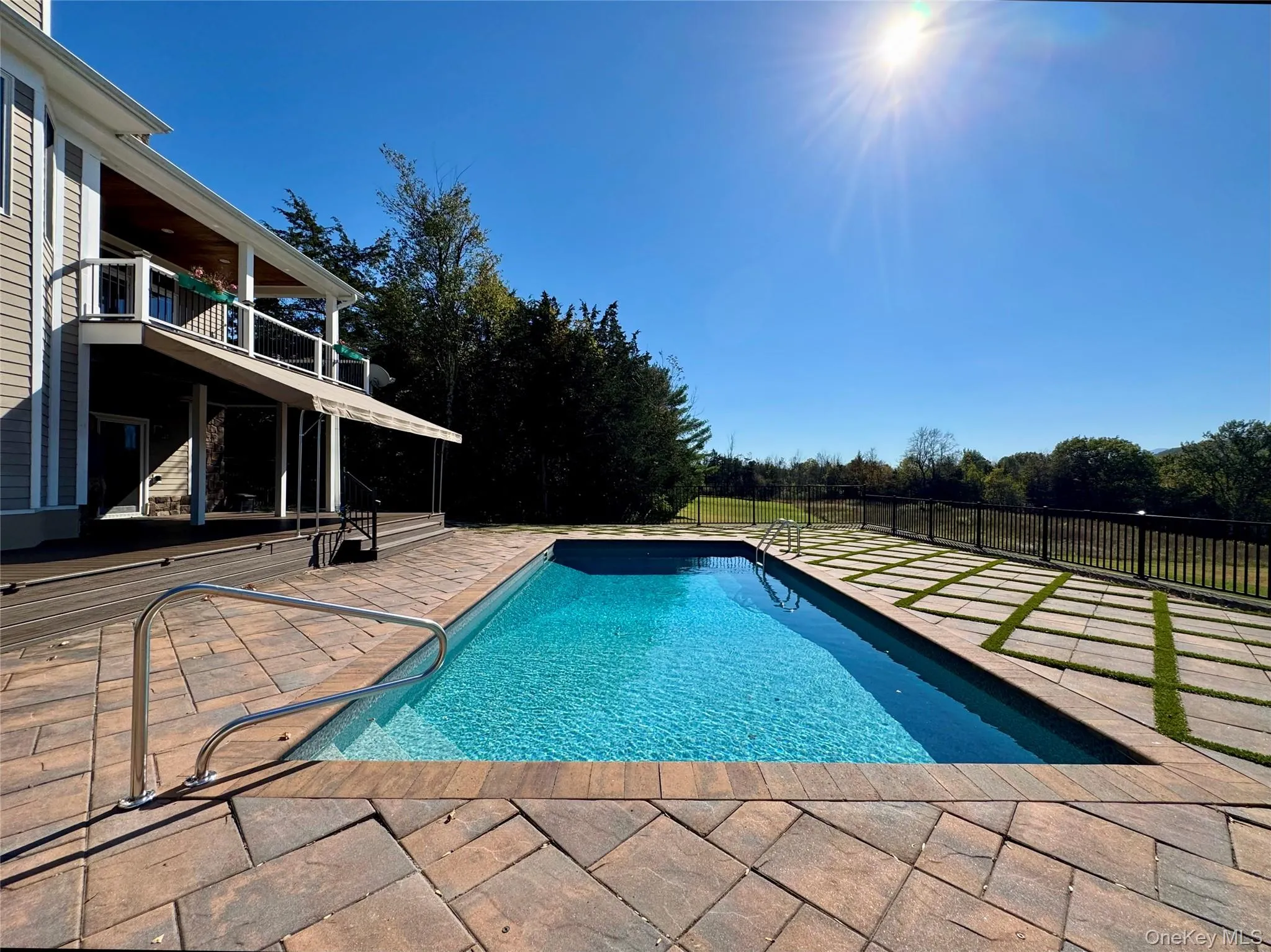 View of pool with a patio area, a balcony, and view of scattered trees View of pool with a patio area, a balcony, and view of scattered trees