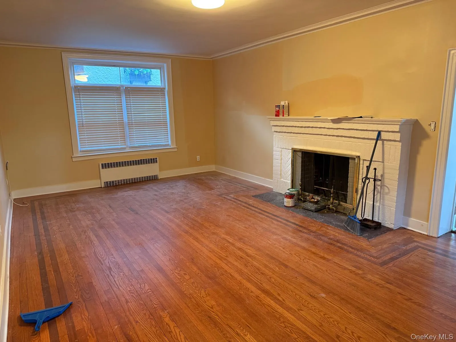 Unfurnished living room with ornamental molding, radiator, hardwood / wood-style floors, and a fireplace Unfurnished living room with ornamental molding, radiator, hardwood / wood-style floors, and a fireplace