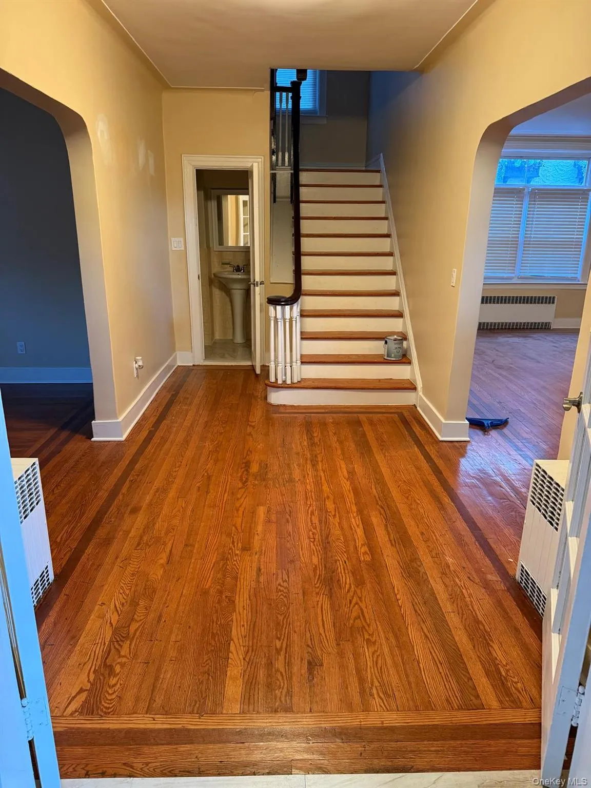 Stairway featuring arched walkways, wood finished floors, and radiator Stairway featuring arched walkways, wood finished floors, and radiator
