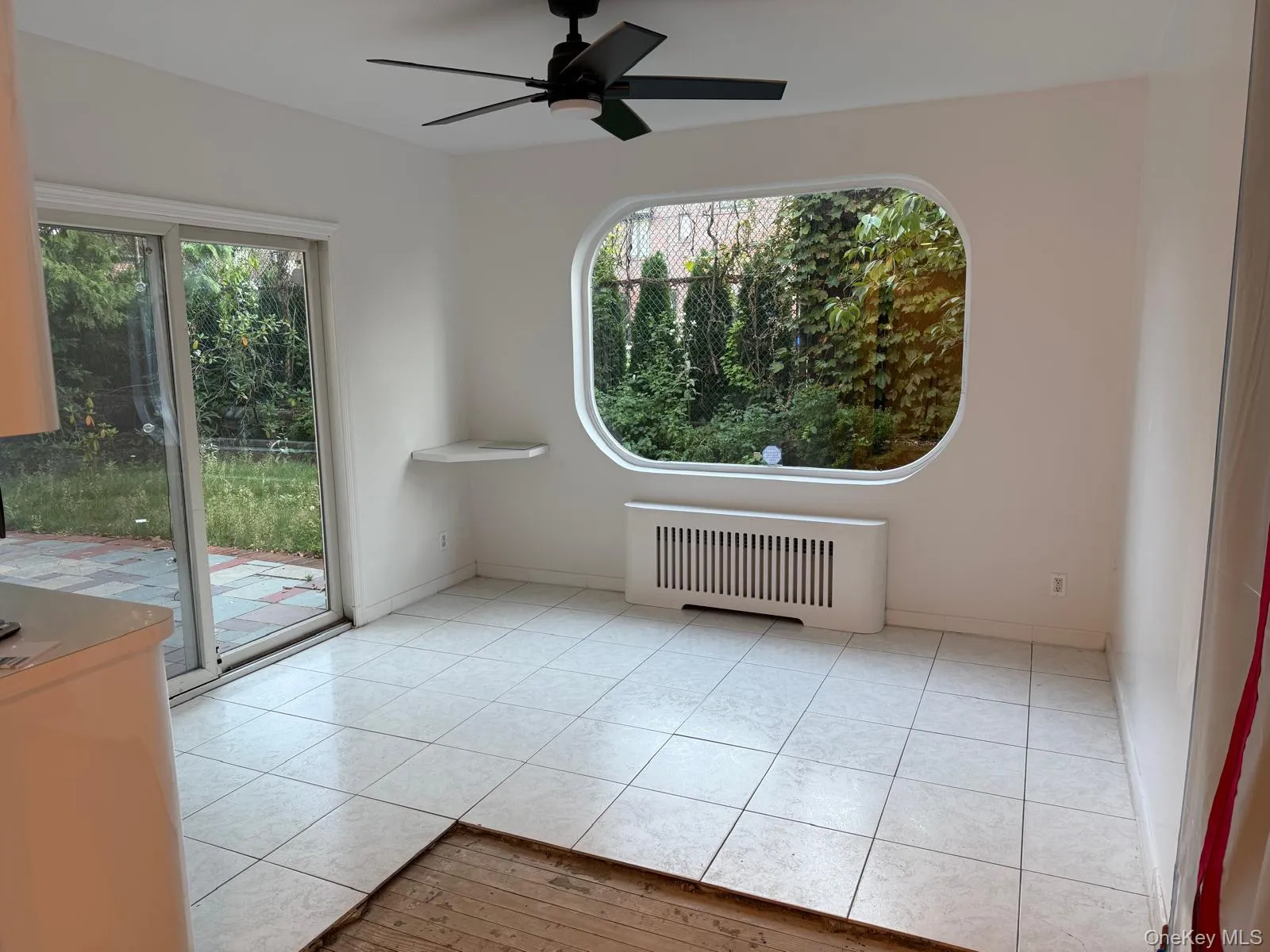 Unfurnished room featuring radiator heating unit, light tile patterned floors, and a ceiling fan Unfurnished room featuring radiator heating unit, light tile patterned floors, and a ceiling fan