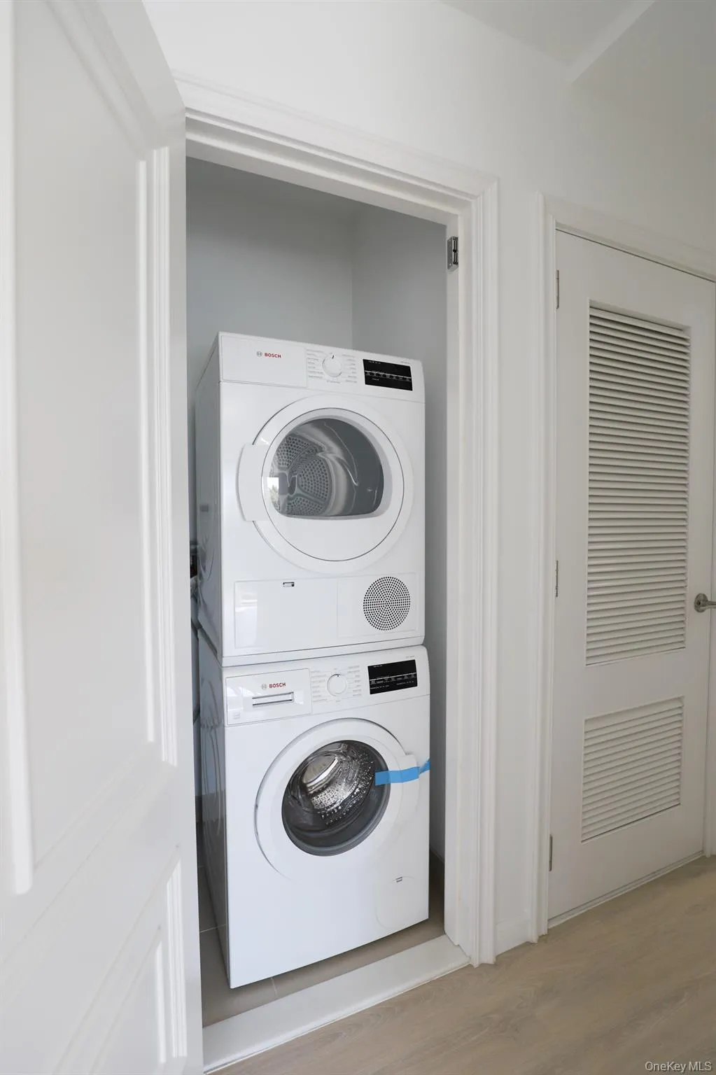 Laundry area featuring estacked washer and dryer and light wood-type flooring Laundry area featuring estacked washer and dryer and light wood-type flooring