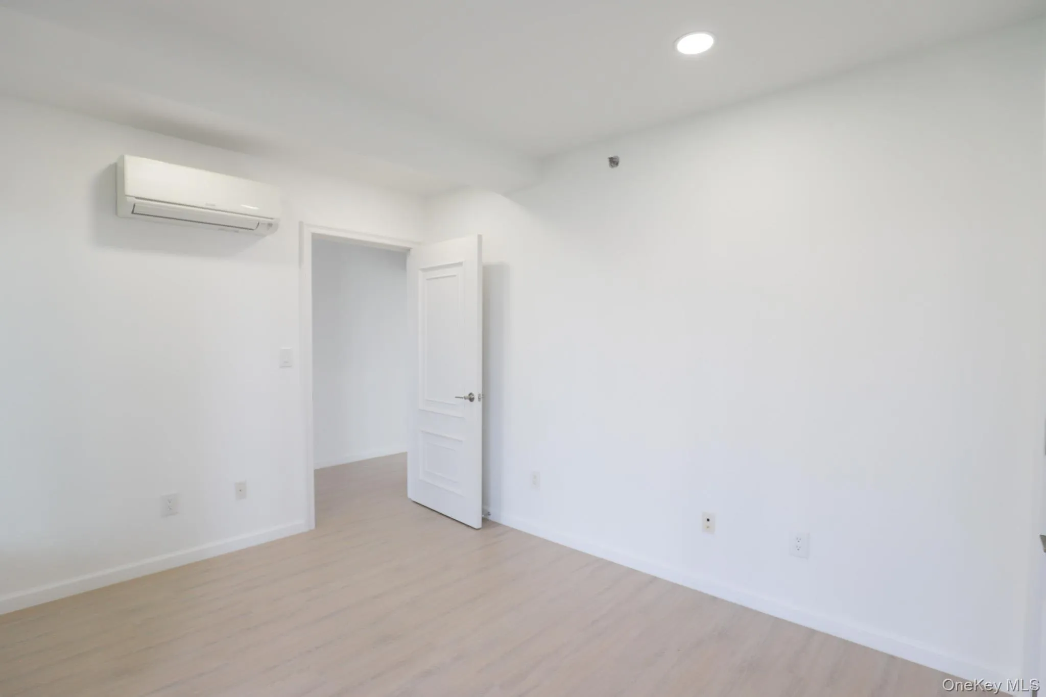 Spare room featuring light wood-type flooring, a wall mounted AC, and recessed lighting Spare room featuring light wood-type flooring, a wall mounted AC, and recessed lighting