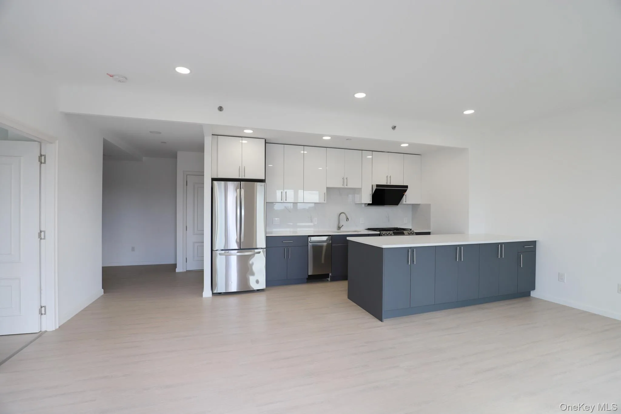 Kitchen featuring white cabinetry, open floor plan, appliances with stainless steel finishes, light wood-style flooring, and recessed lighting Kitchen featuring white cabinetry, open floor plan, appliances with stainless steel finishes, light wood-style flooring, and recessed lighting