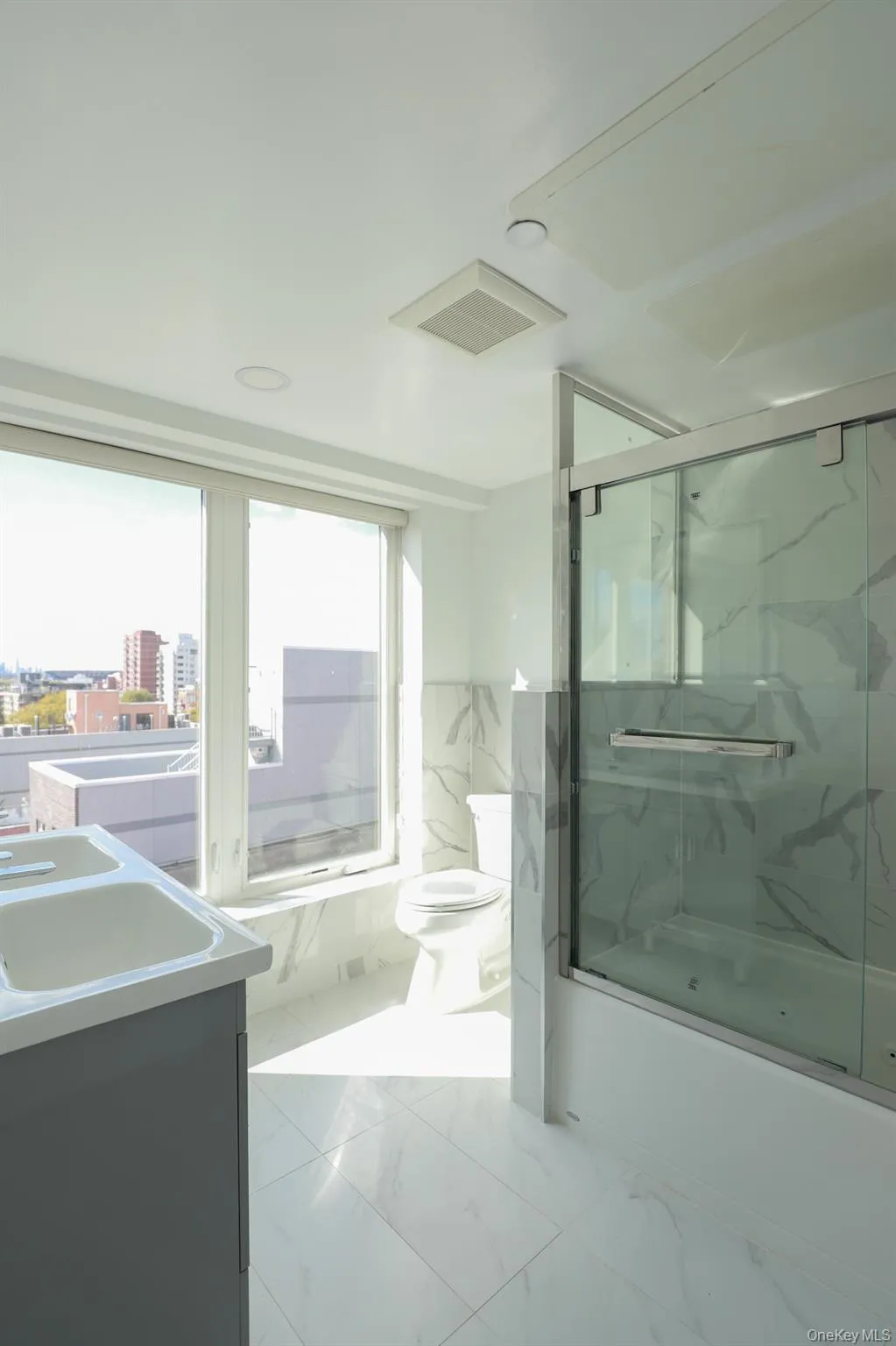 Full bathroom featuring light marble finish floors, vanity, a marble finish shower, and tile walls Full bathroom featuring light marble finish floors, vanity, a marble finish shower, and tile walls