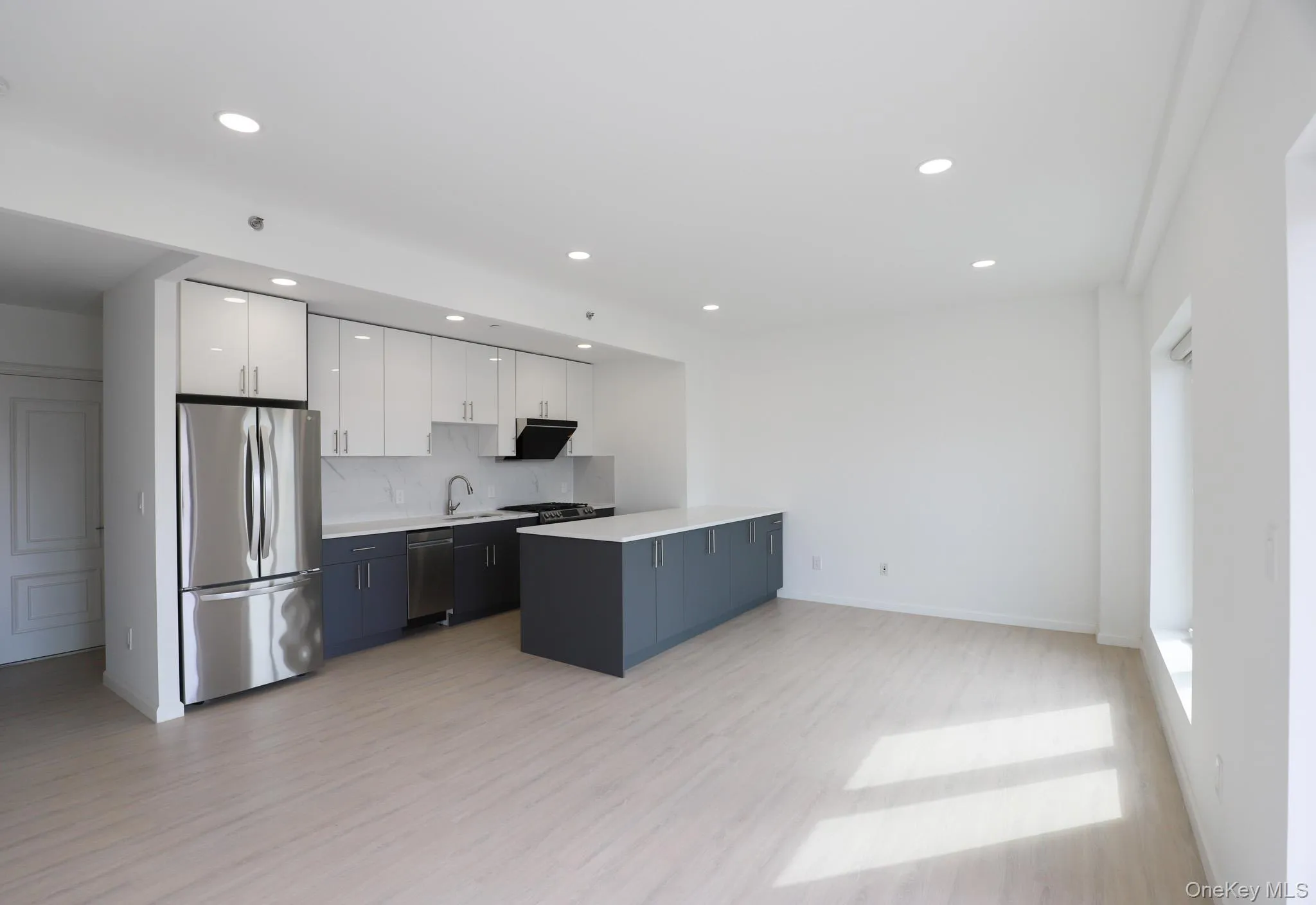 Kitchen featuring white cabinetry, stainless steel appliances, open floor plan, light wood-type flooring, and recessed lighting Kitchen featuring white cabinetry, stainless steel appliances, open floor plan, light wood-type flooring, and recessed lighting