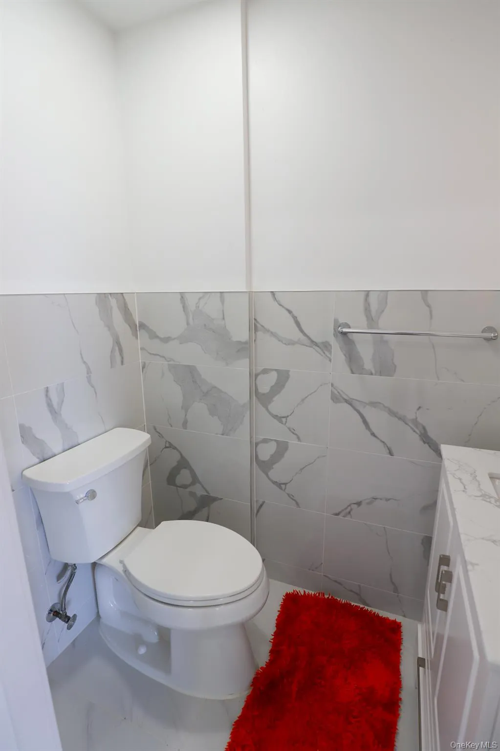 Half bath featuring tile walls, vanity, and wainscoting Half bath featuring tile walls, vanity, and wainscoting