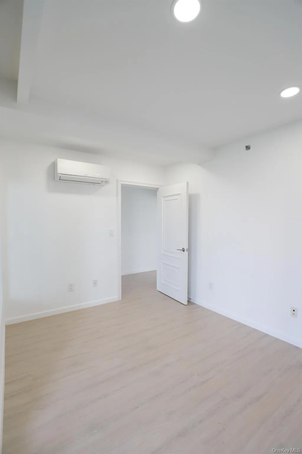 Below grade area with light wood-type flooring, recessed lighting, and an AC wall unit Below grade area with light wood-type flooring, recessed lighting, and an AC wall unit