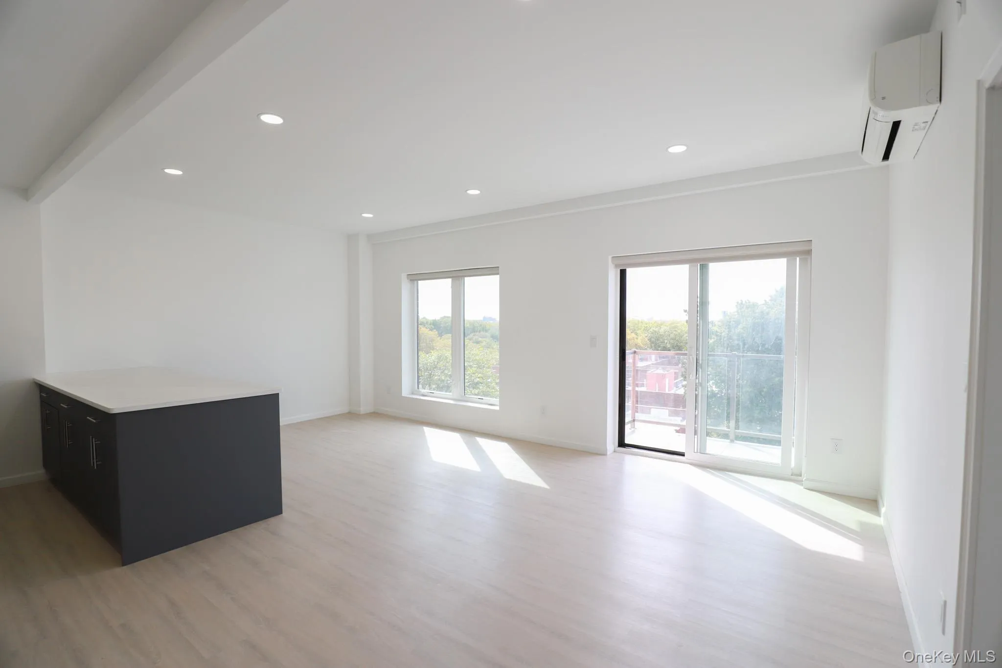 Unfurnished living room with light wood finished floors, recessed lighting, and a wall mounted AC Unfurnished living room with light wood finished floors, recessed lighting, and a wall mounted AC