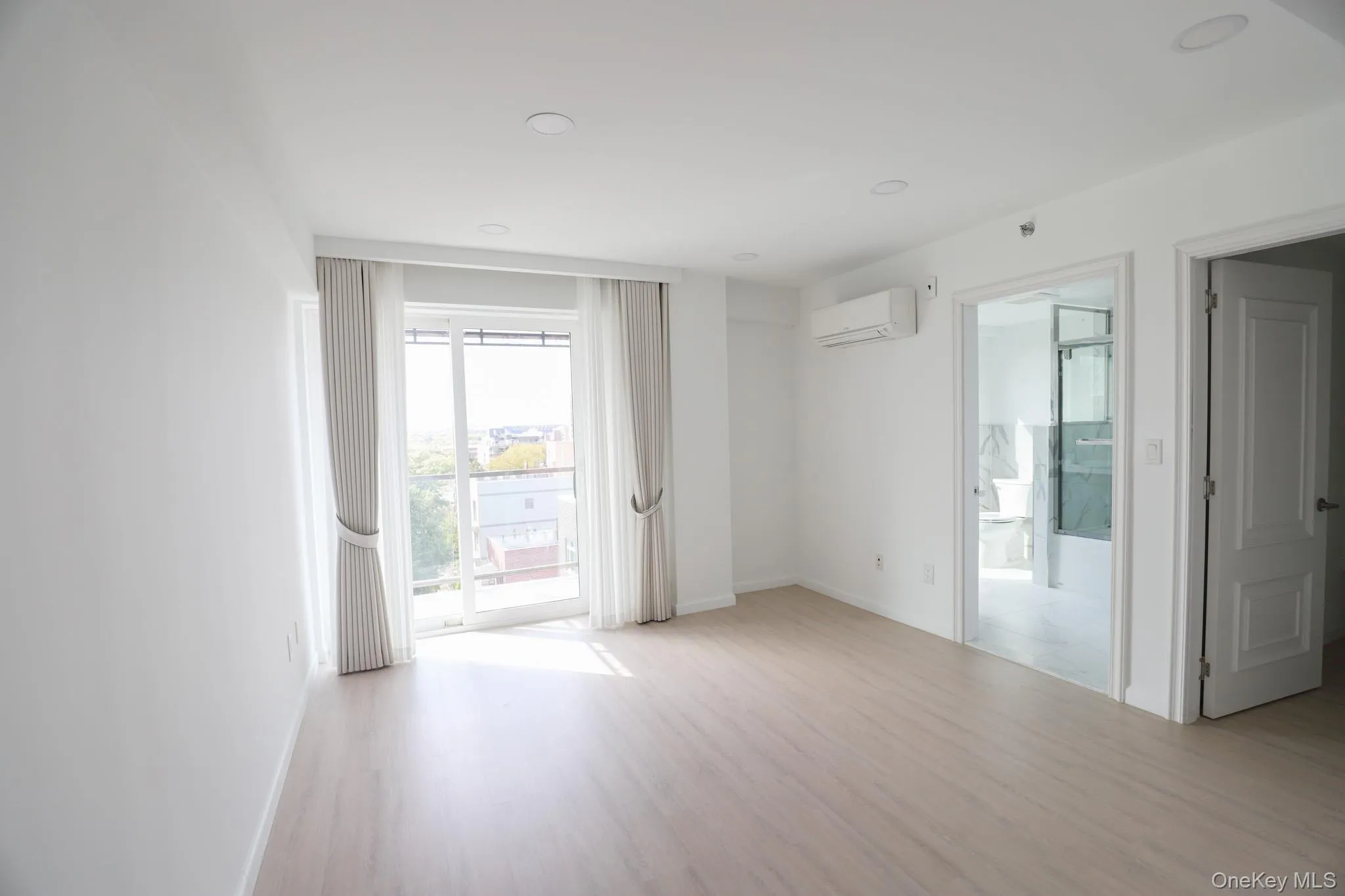 Unfurnished room with light wood-style flooring, recessed lighting, and a wall mounted air conditioner Unfurnished room with light wood-style flooring, recessed lighting, and a wall mounted air conditioner
