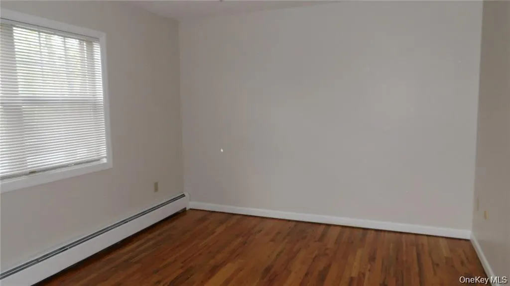 Empty room featuring a baseboard radiator and dark wood-style floors Empty room featuring a baseboard radiator and dark wood-style floors